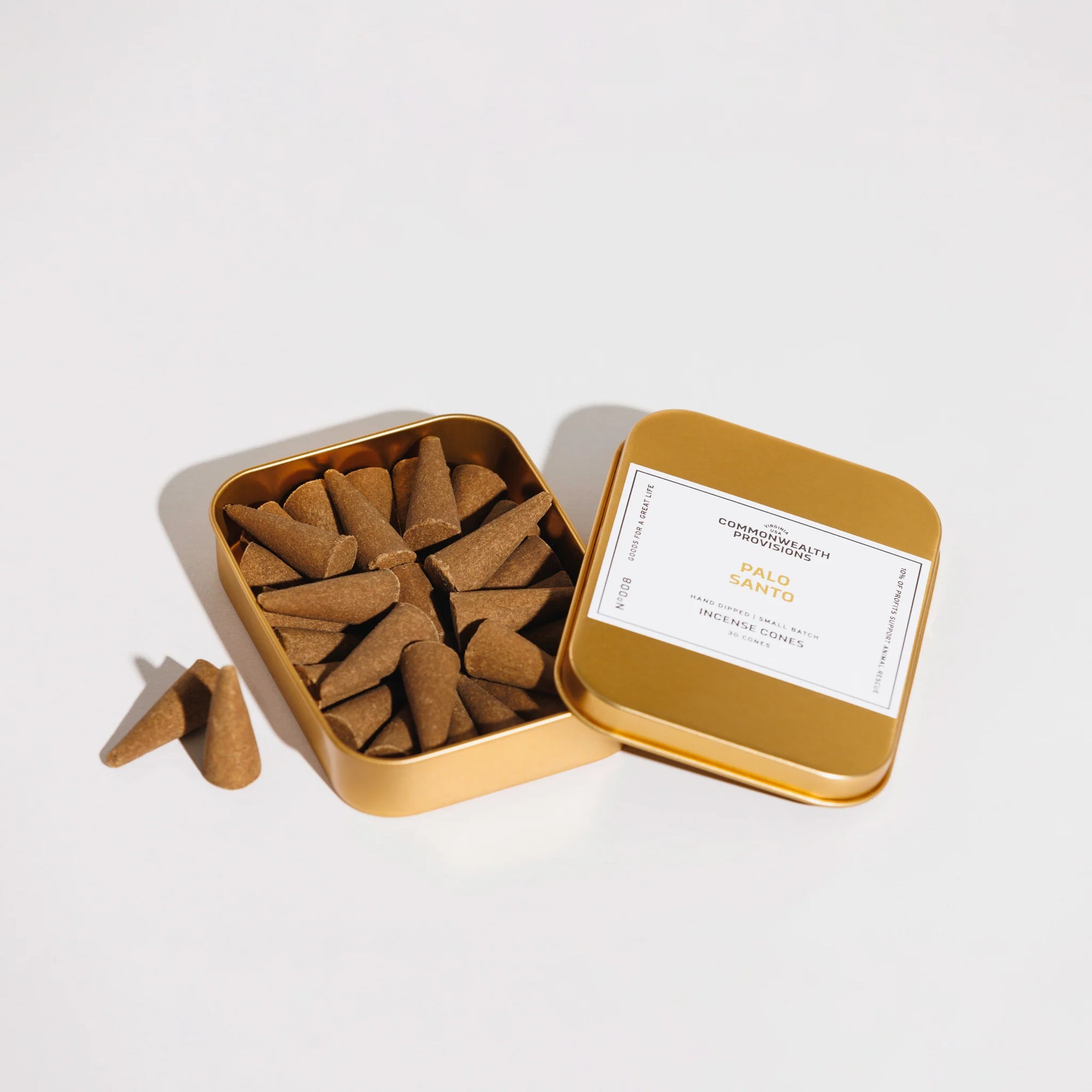 Open gold tin of Palo Santo incense cones with label from Commonwealth Provisions on white background
