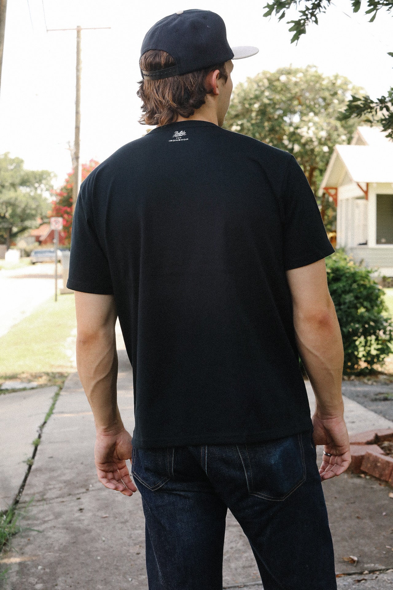 Man wearing black Iron Shop Provisions Buffalo Nickel Coffin Loopwheel T-shirt and dark jeans outdoors