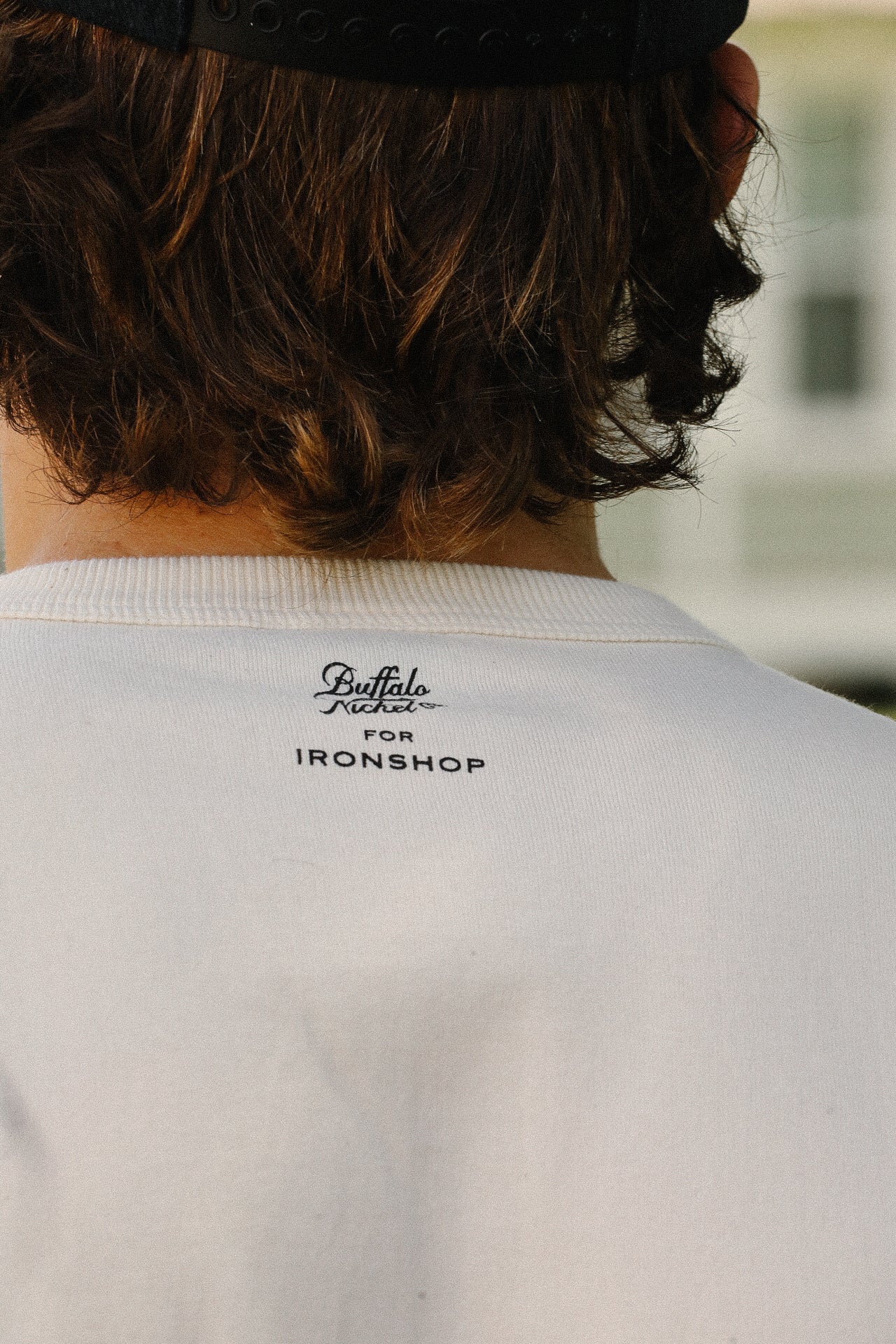 Back view of person wearing cream loopwheel tee with Buffalo Nickel for Ironshop logo on neck