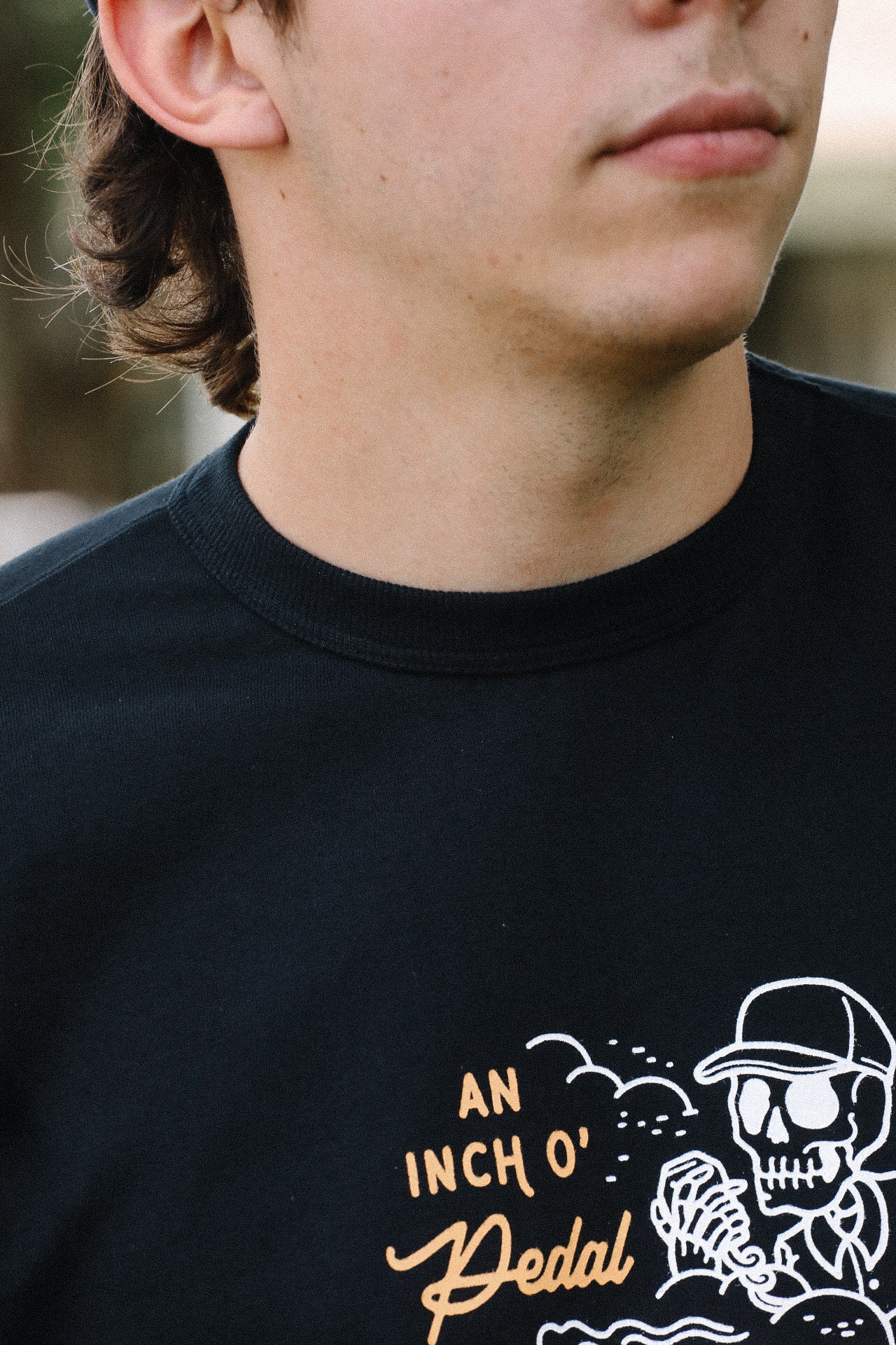 Close-up of a man wearing a black Iron Shop Provisions tee with white skeleton and orange text graphic