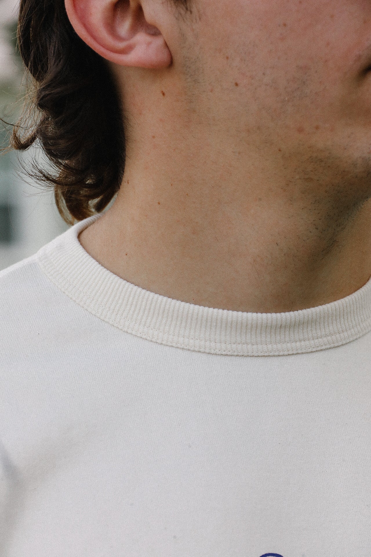 Close-up of a person wearing a cream loopwheel t-shirt from Iron Shop Provisions with visible neckline and textured fabric