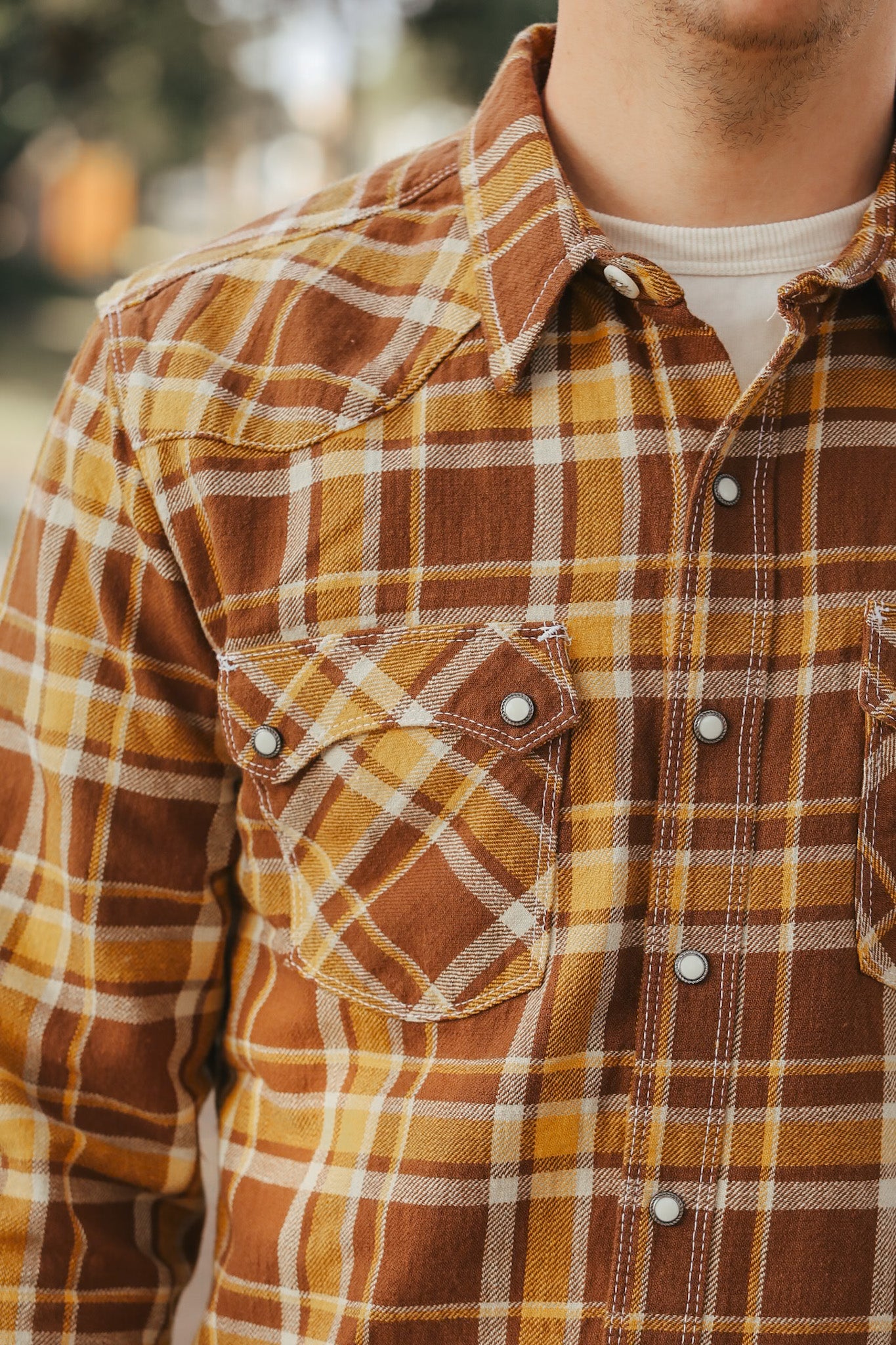 Close-up of a person wearing a brown and orange plaid shirt.