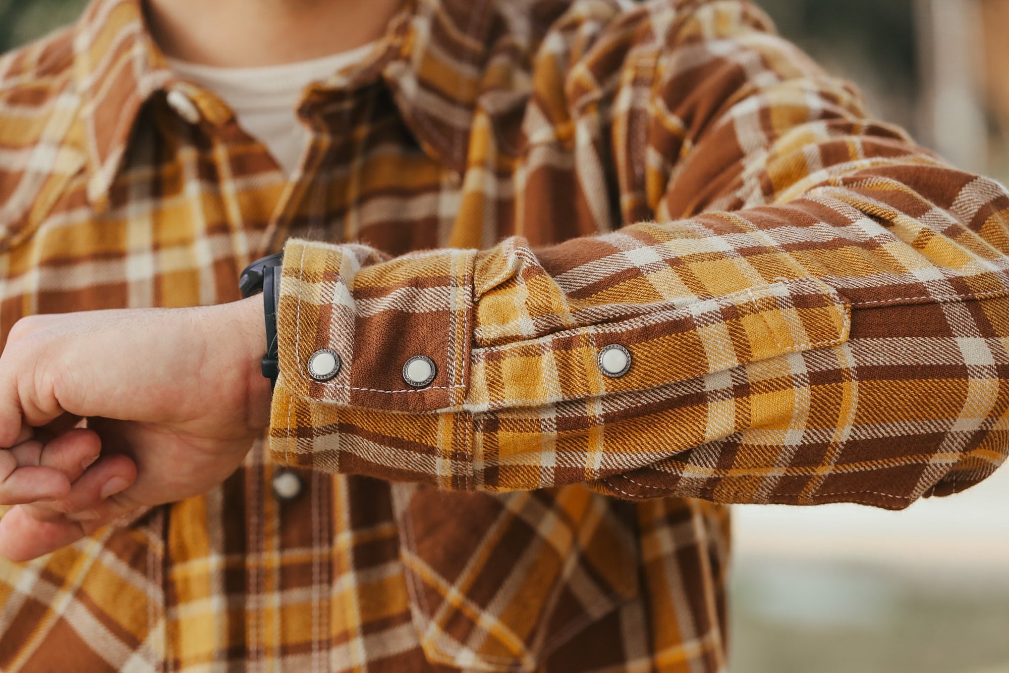 Close-up of a person wearing a plaid shirt with rolled-up sleeves.