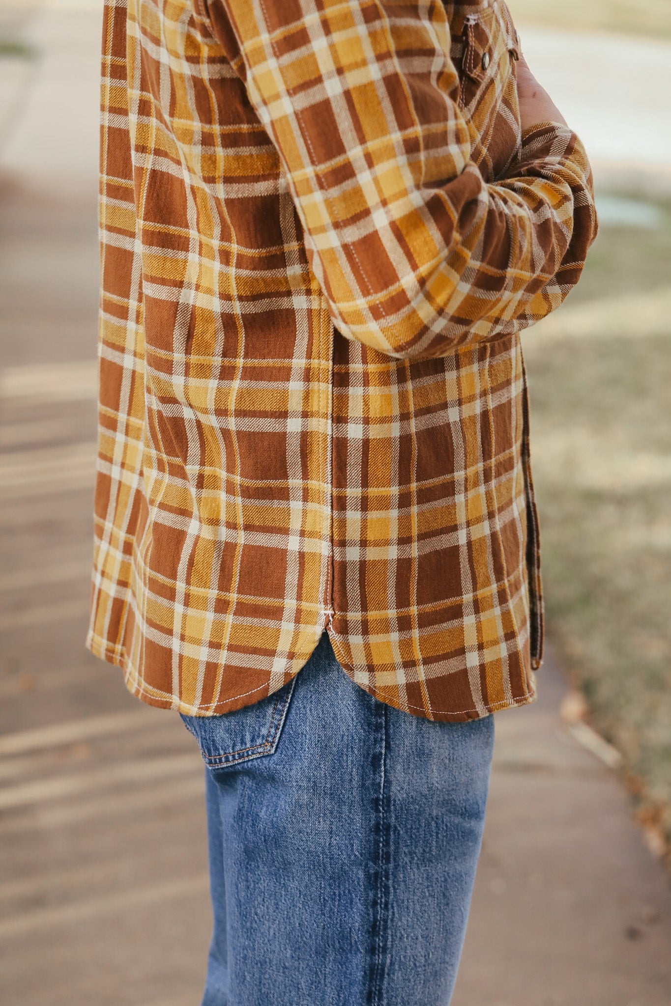 Person wearing a plaid shirt and jeans with a blurred background