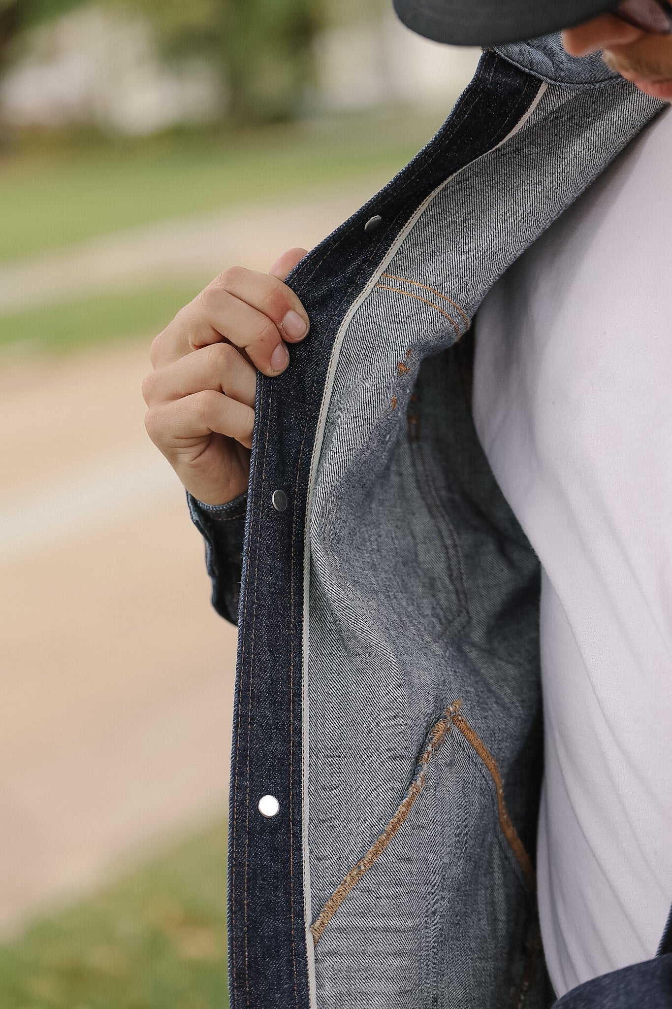 Person wearing a denim jacket with a blurred outdoor background