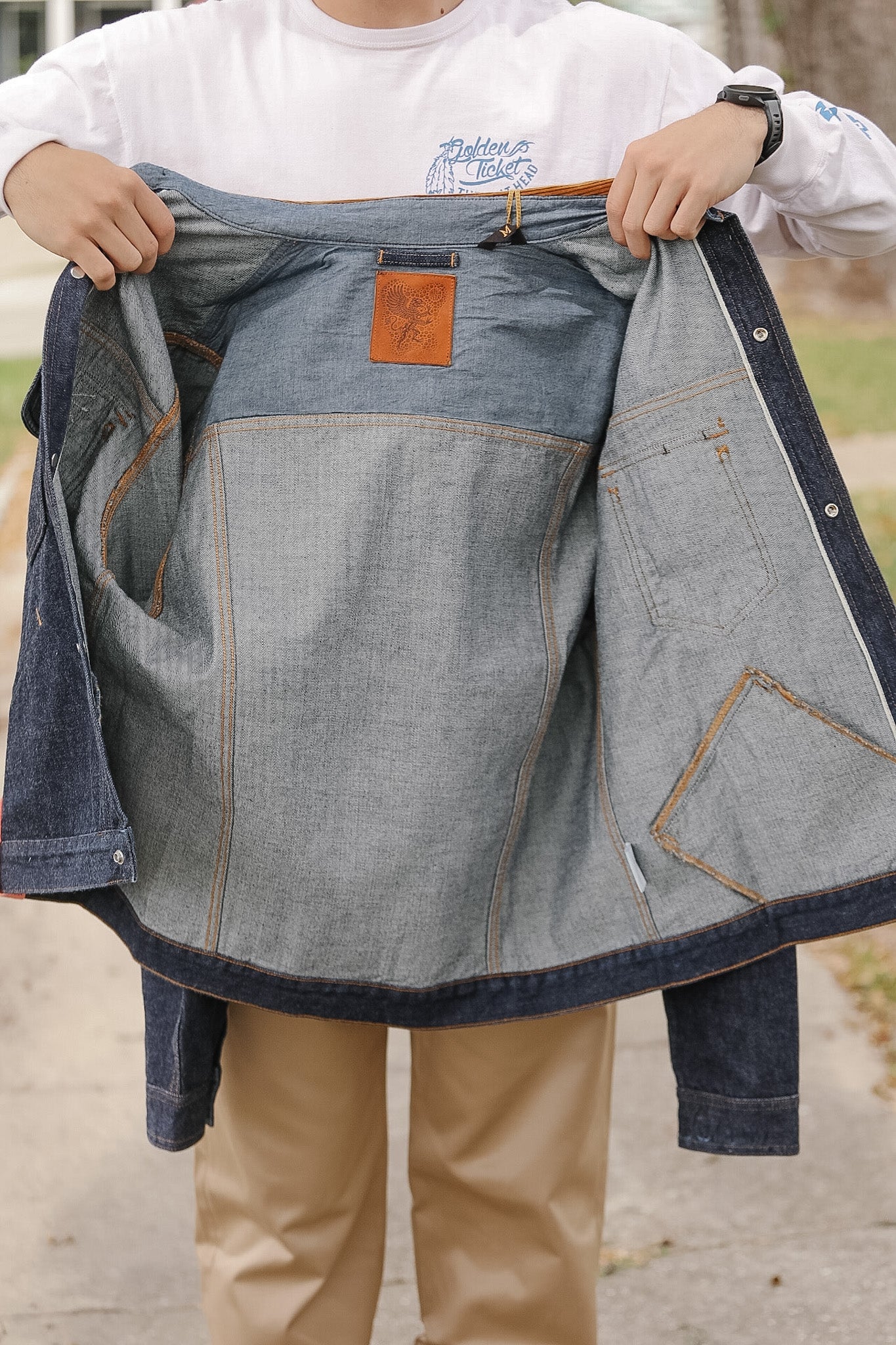 Person holding a denim apron with a visible brand logo.