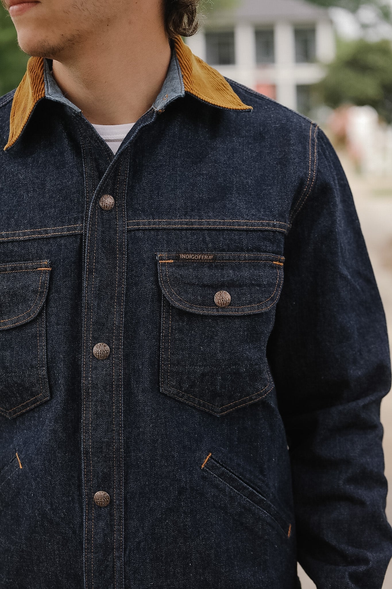 Person wearing a dark denim jacket with yellow collar and buttons.