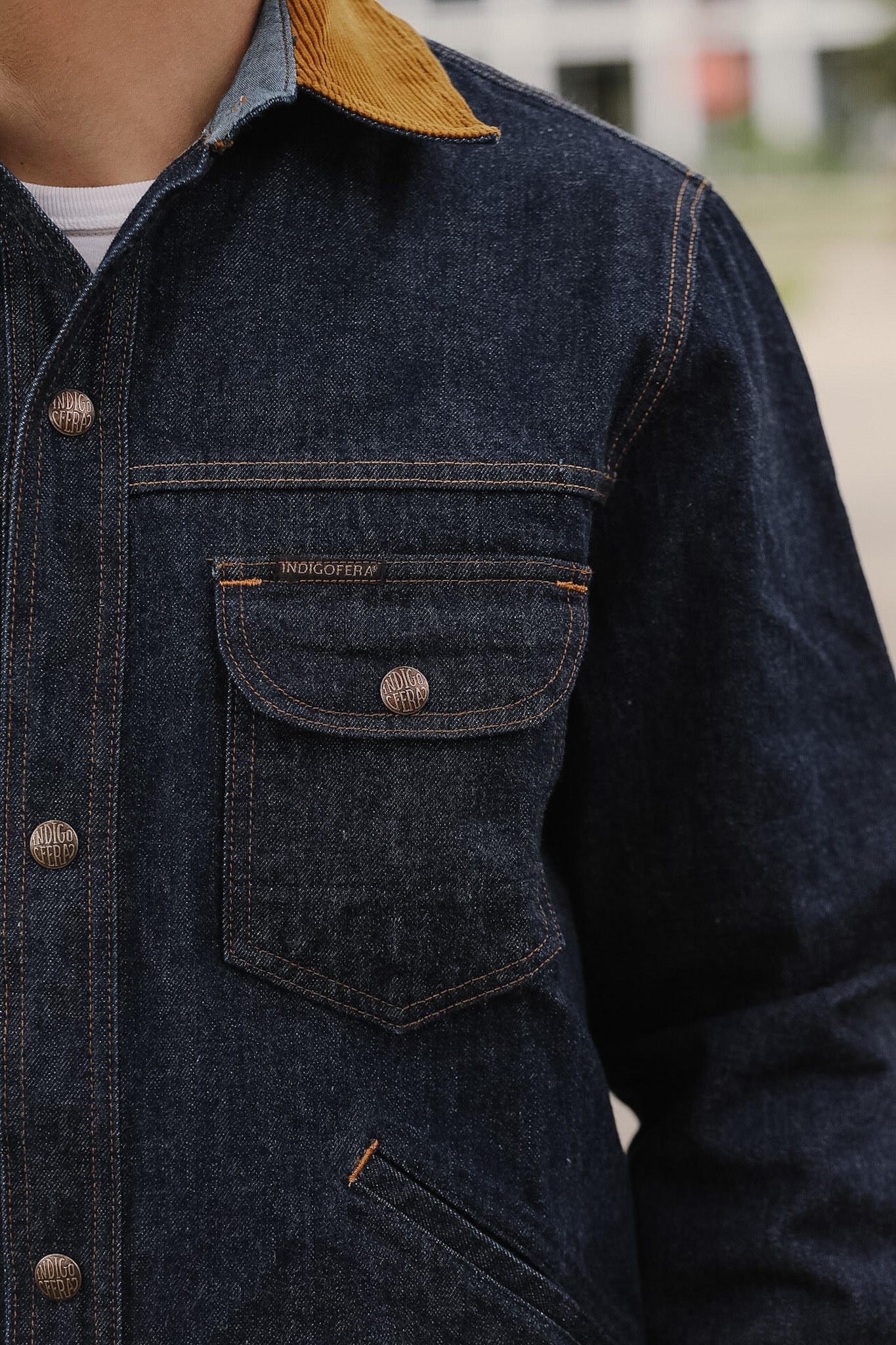 Close-up of a dark denim jacket with a yellow collar and visible brand name.
