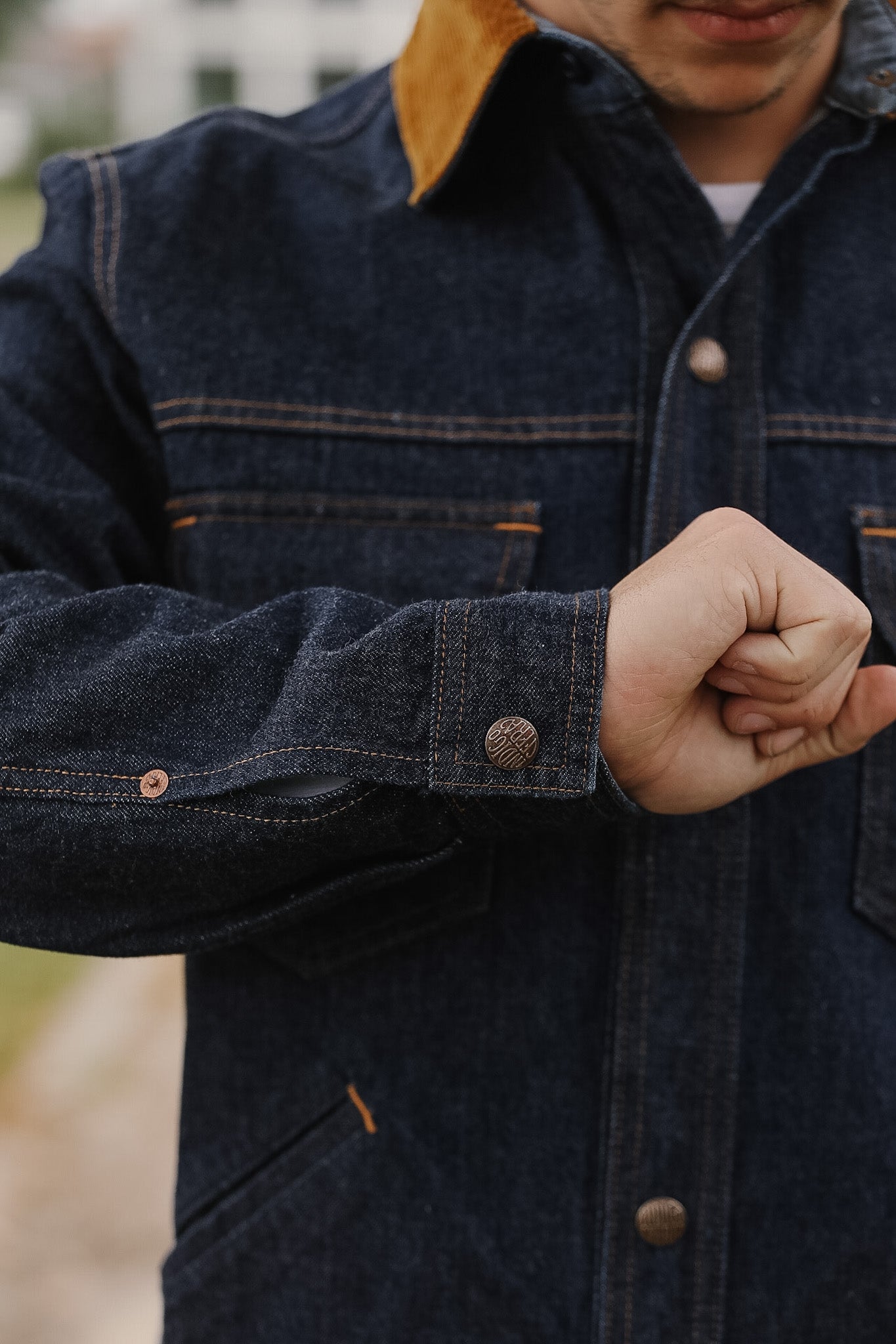 Person wearing a dark denim jacket with a blurred background