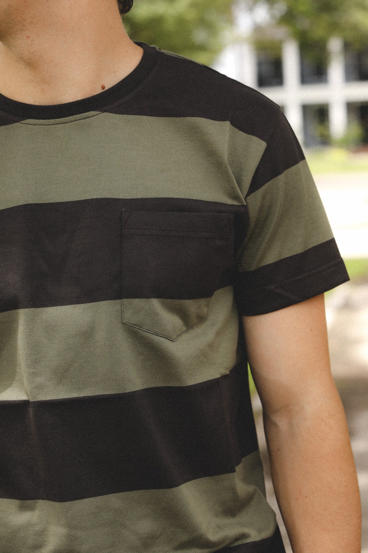 Person wearing a green and black striped shirt outdoors