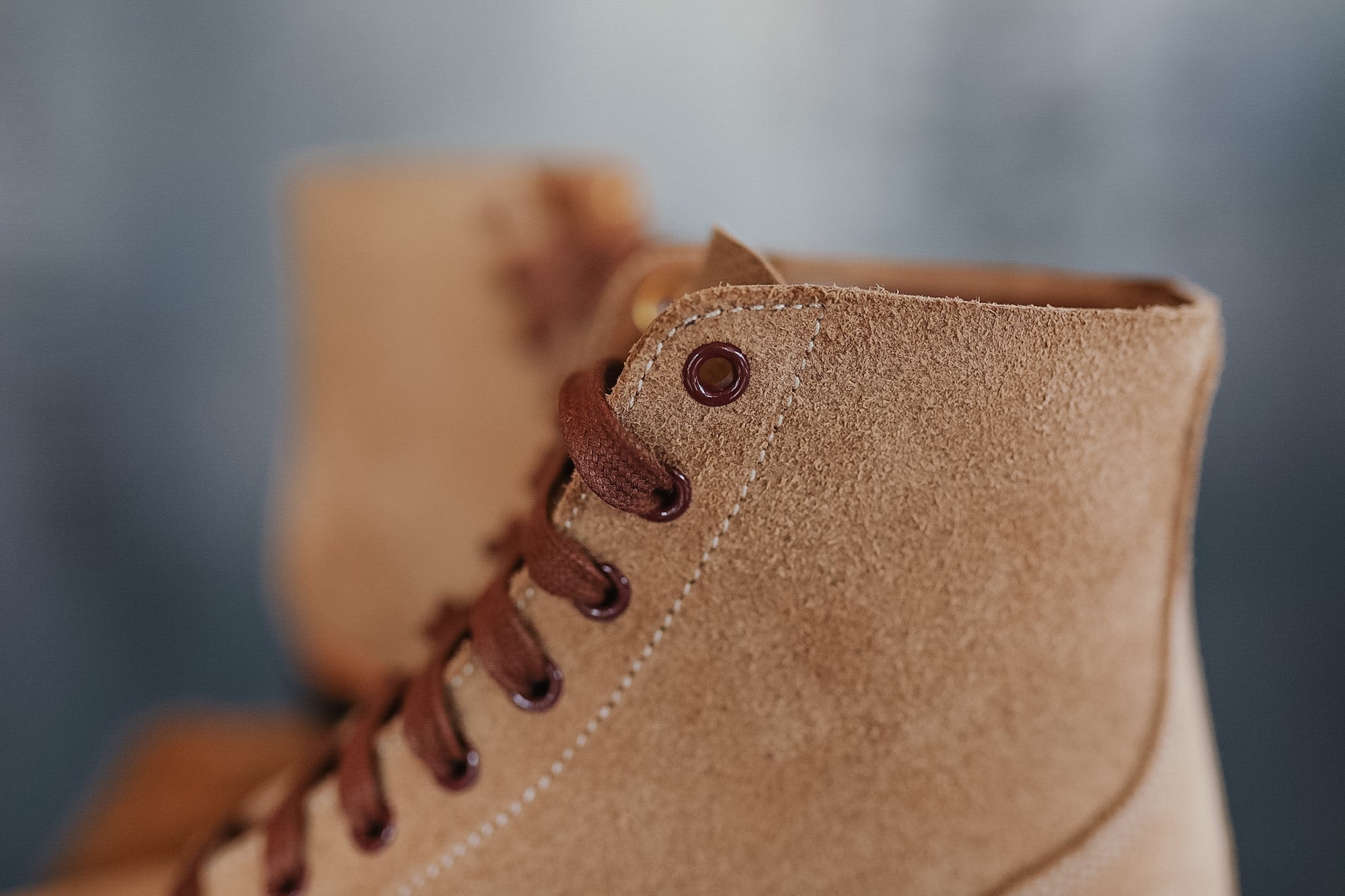 Close-up of a brown suede boot with leather laces on a blurred background