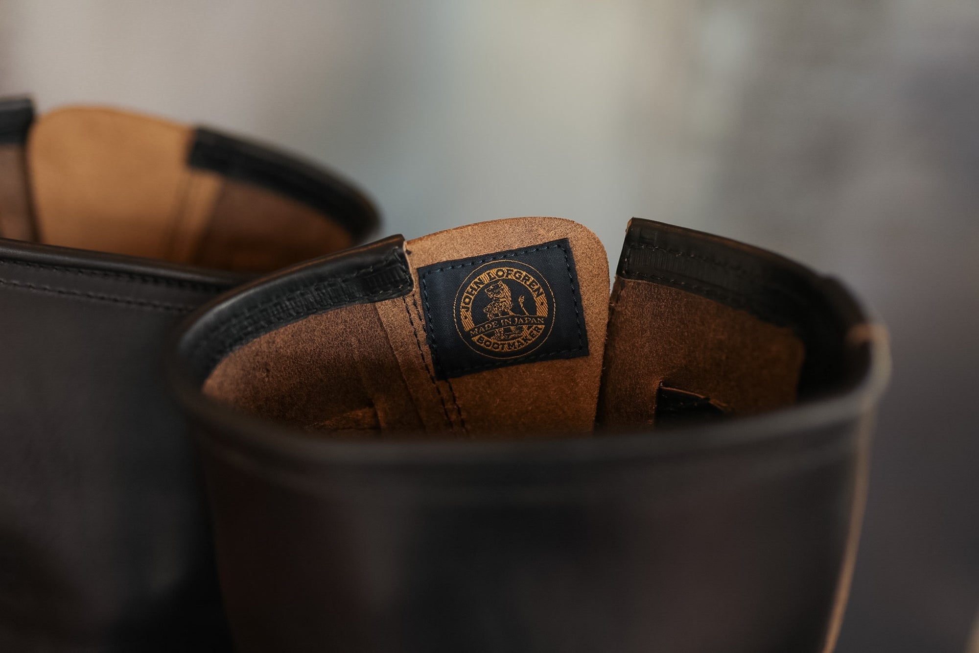 Brown leather shoes with a visible brand logo in a black container on a blurred background