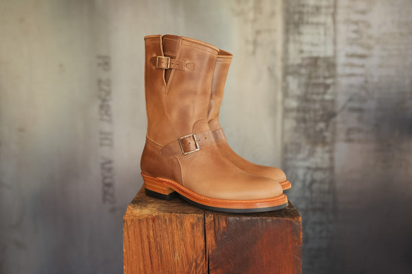 Pair of brown leather boots on a wooden block with a textured background