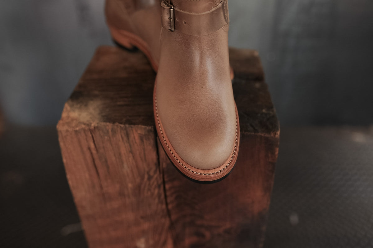 Brown leather boot on a wooden block with a blurred background