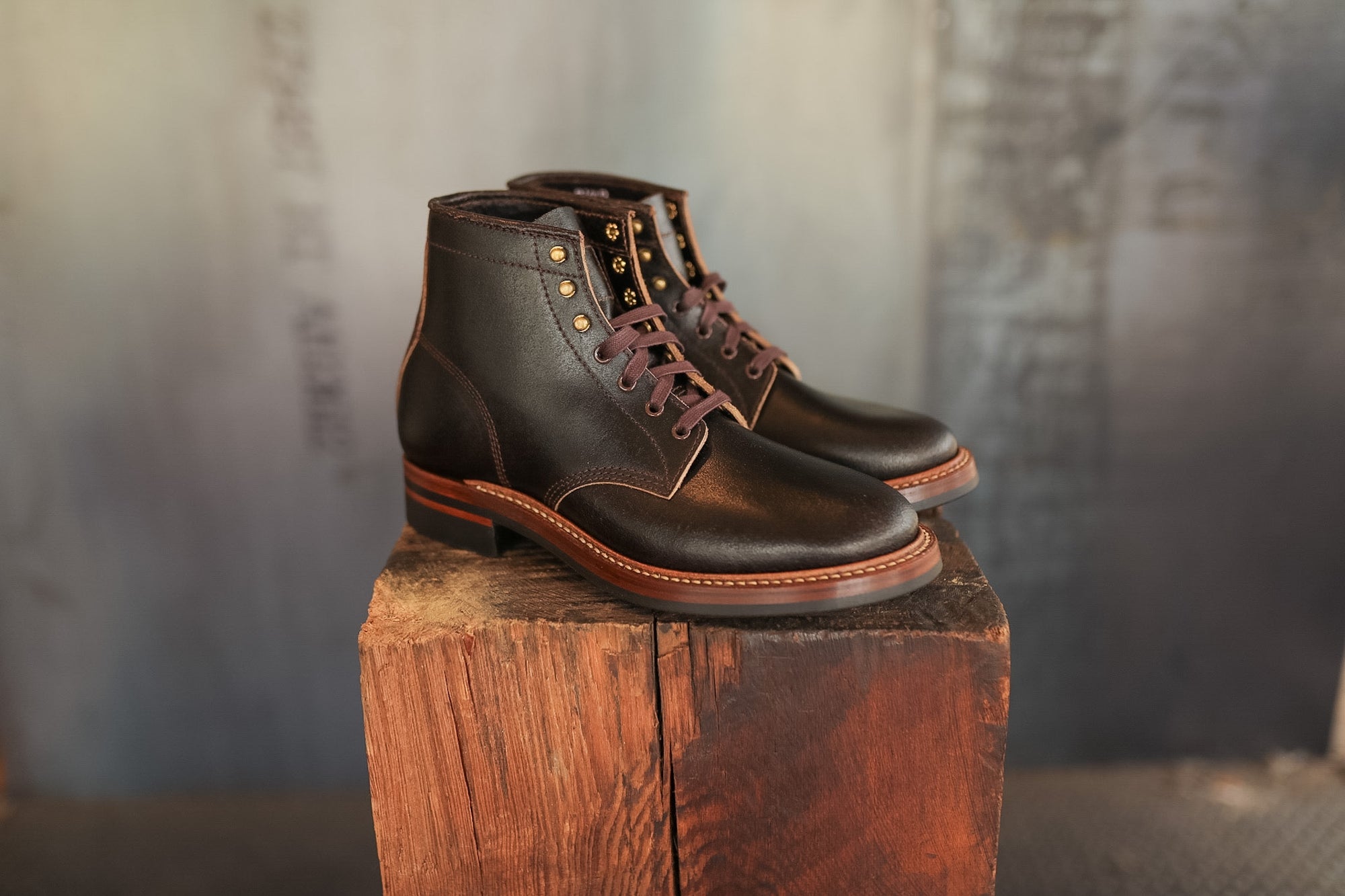 Pair of brown leather boots on a wooden block with a blurred background
