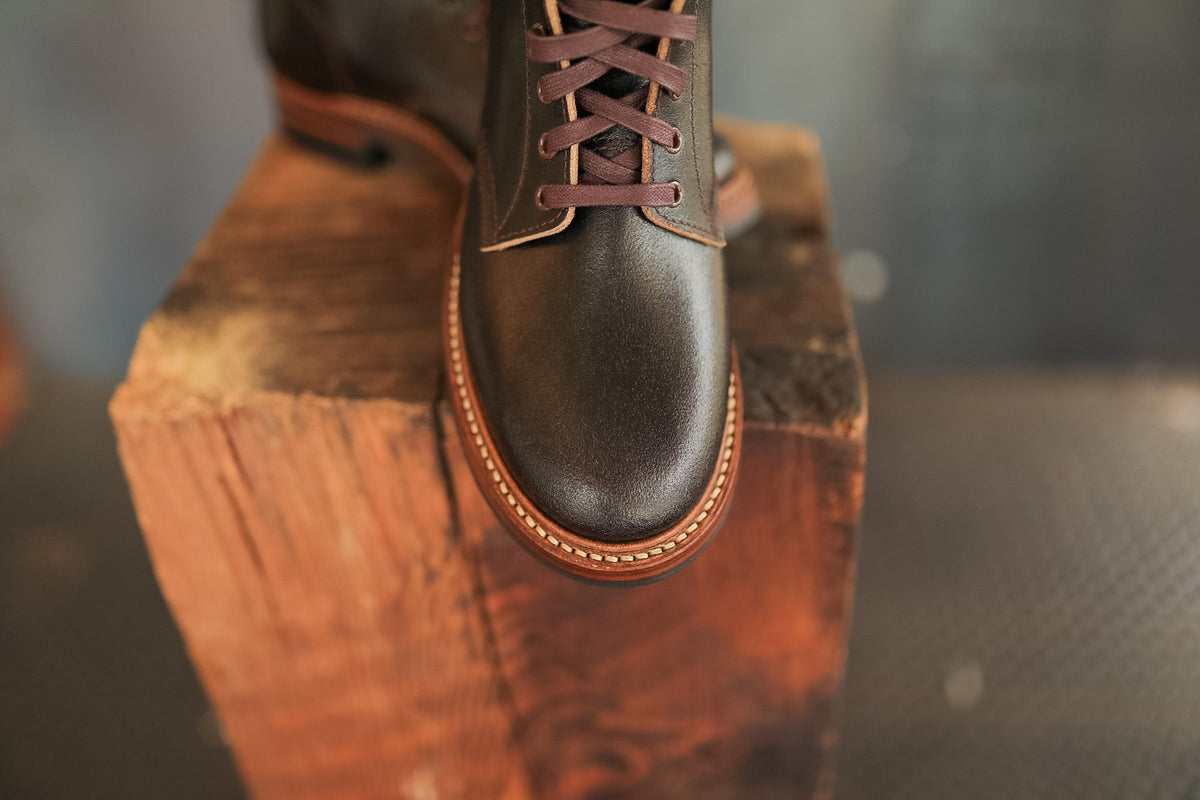 Brown leather boot on a wooden block with a blurred background