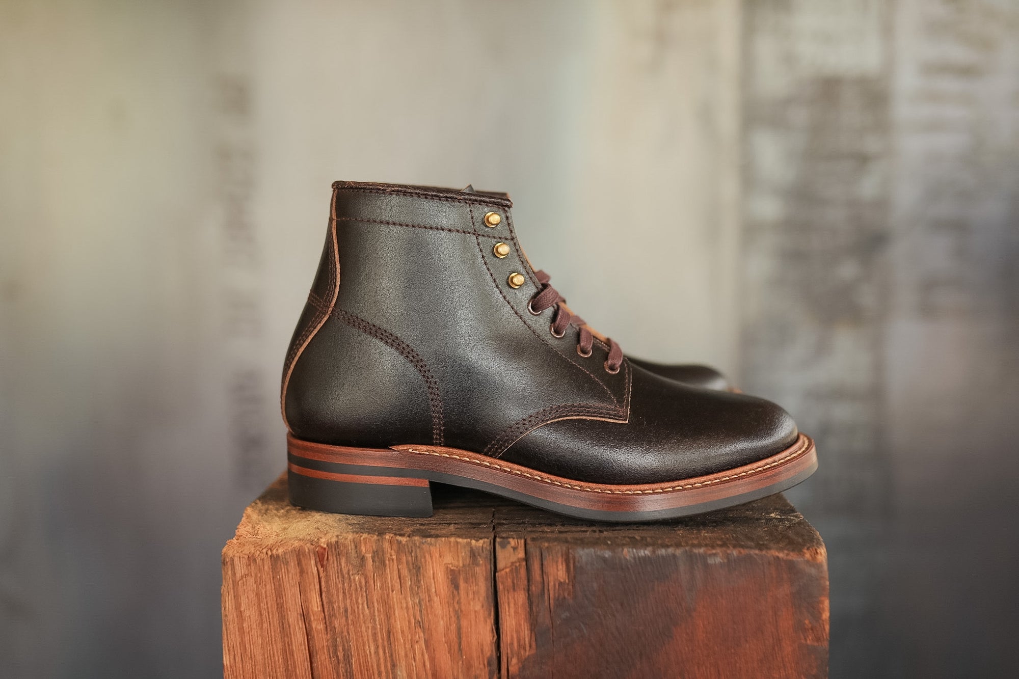 Pair of brown leather boots on a wooden block with a blurred background