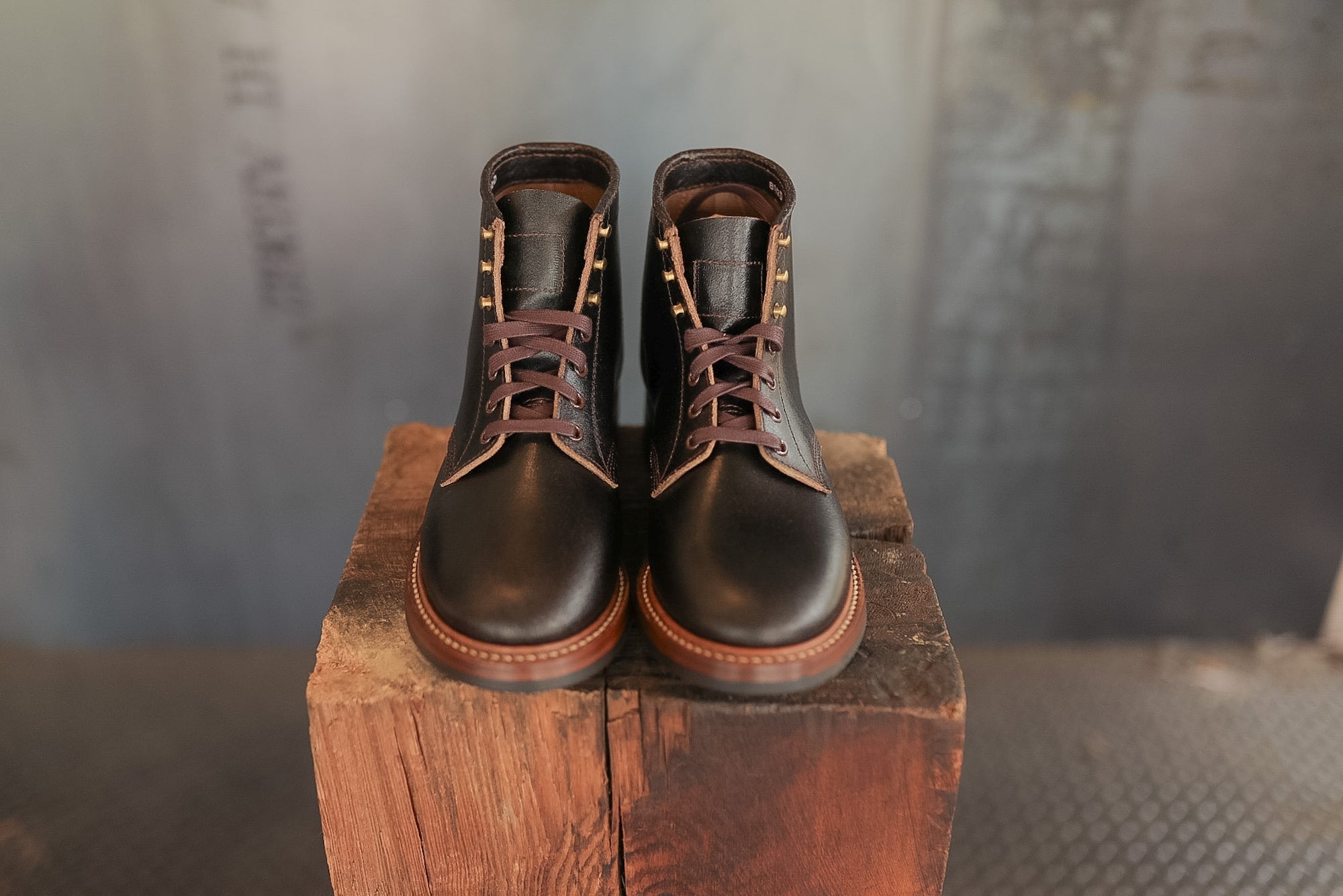 Pair of black leather boots on a wooden block with a blurred background