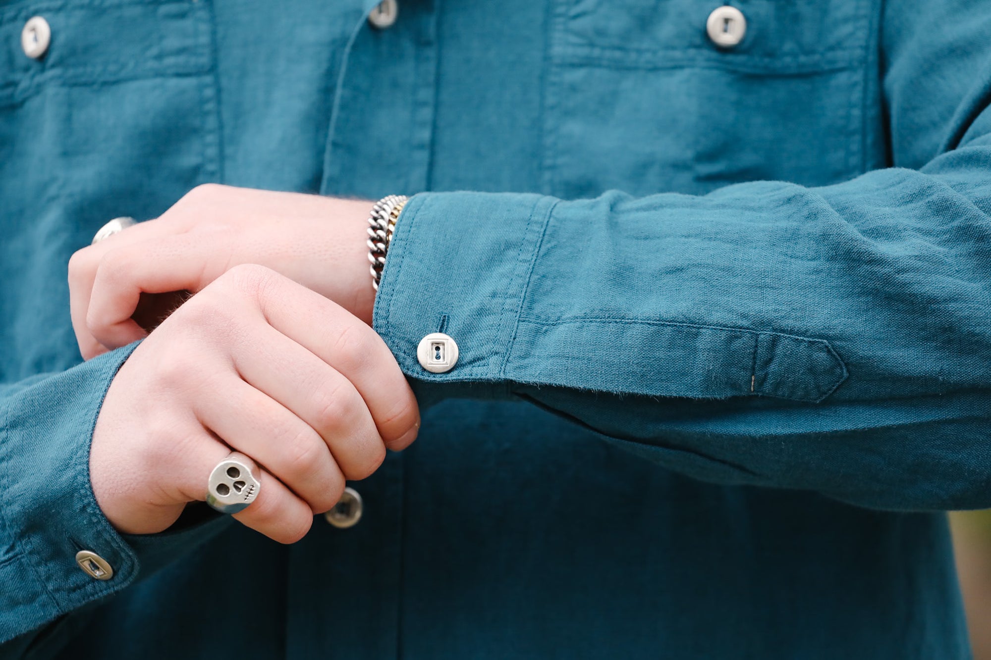 Person wearing a blue jacket with rolled-up sleeve, showing a ring on a finger.