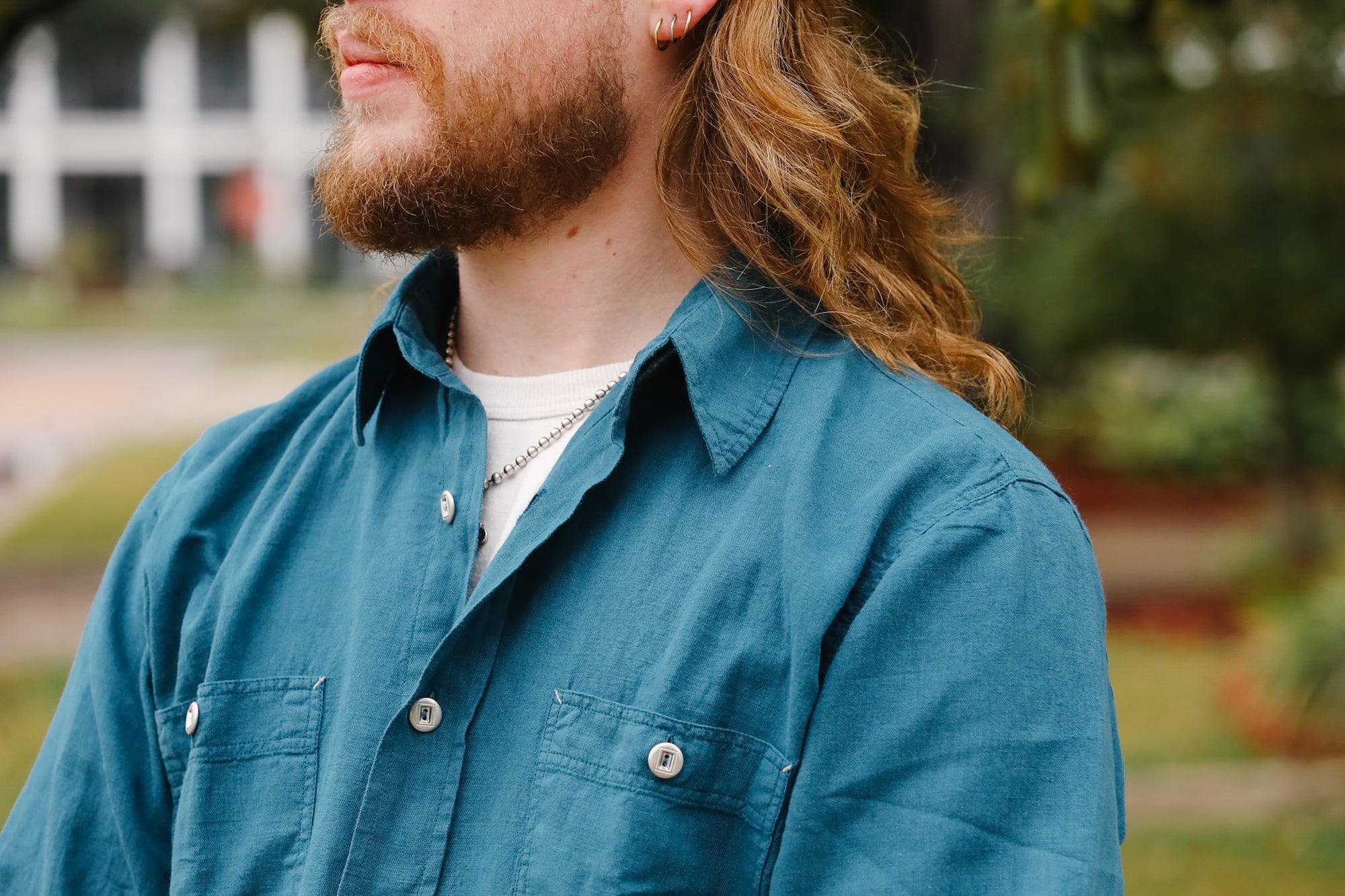 Man wearing a blue shirt with a blurred outdoor background