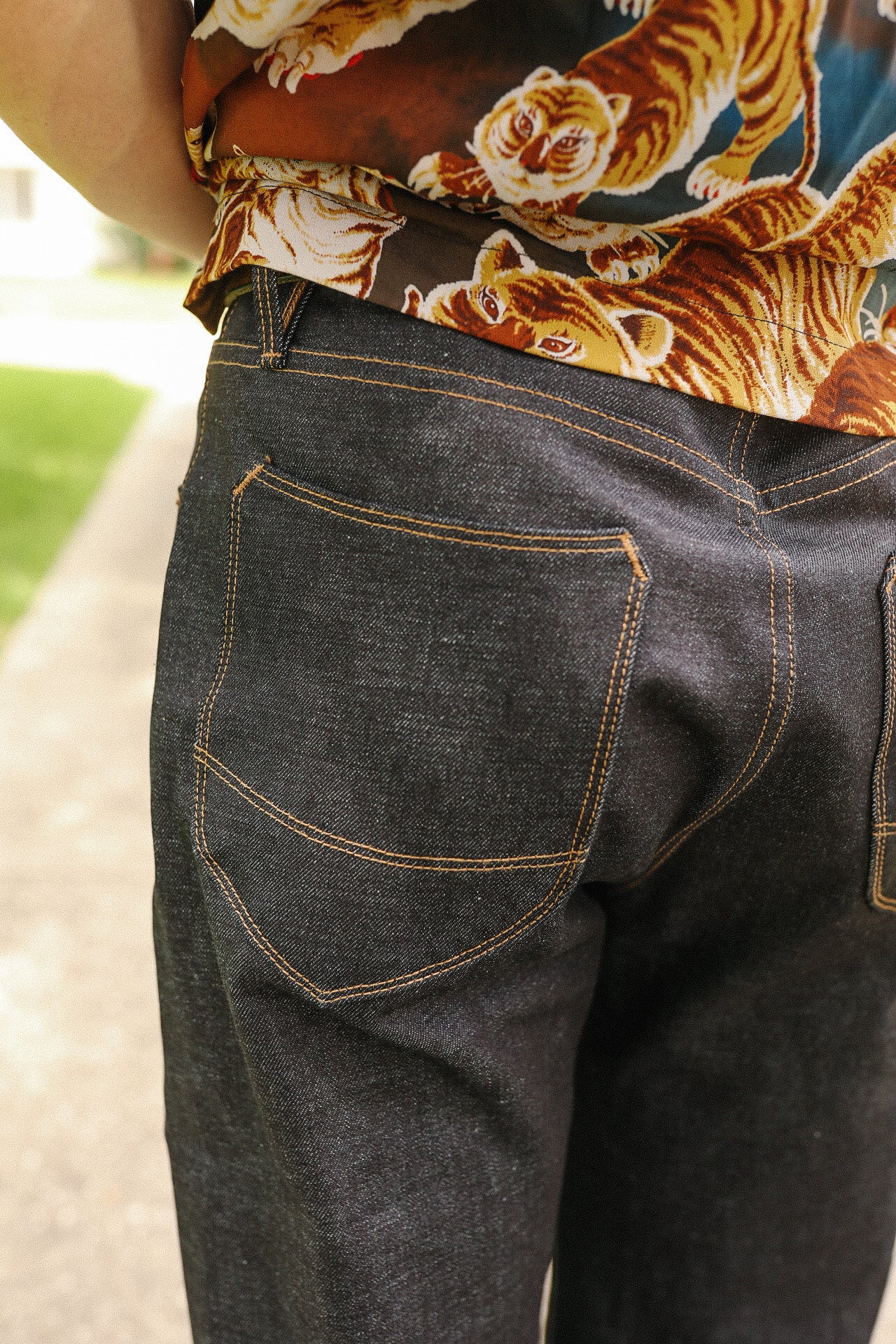 Close-up of dark raw denim jeans with orange stitching and tiger print shirt at Iron Shop Provisions