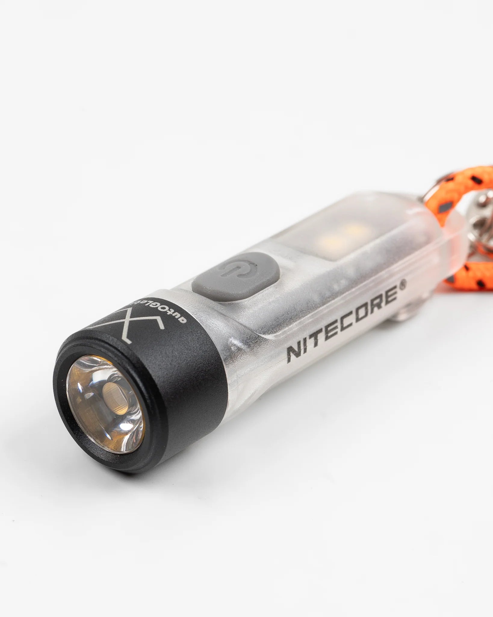 Close-up of a Nitecore transparent keychain flashlight with black head, gray power button, and orange lanyard