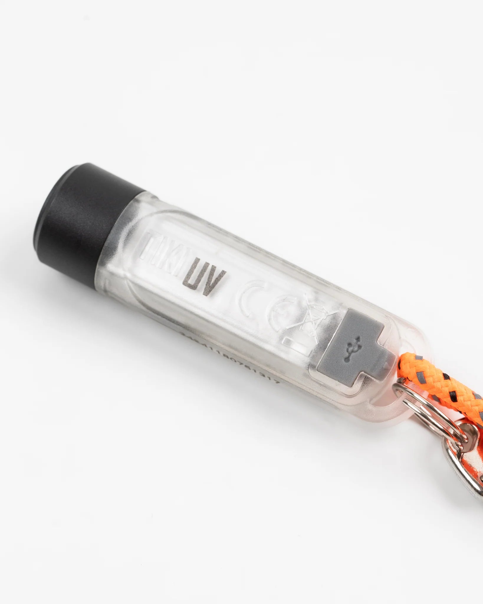 Compact transparent UV flashlight keychain with black cap and orange braided lanyard on white background