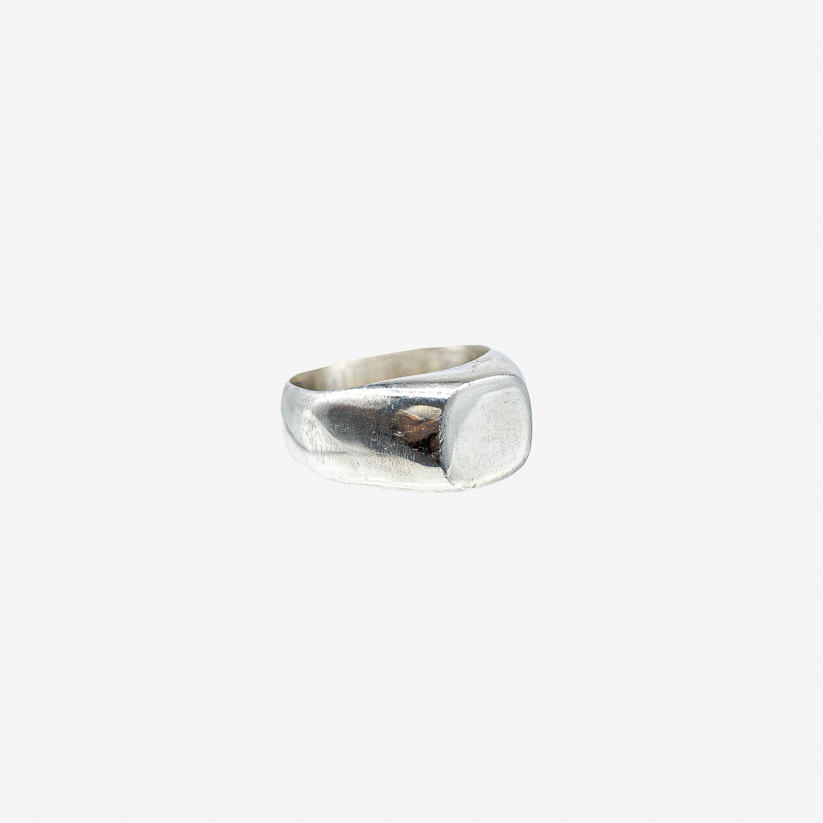 Polished silver signet ring with a smooth, square face on a white background