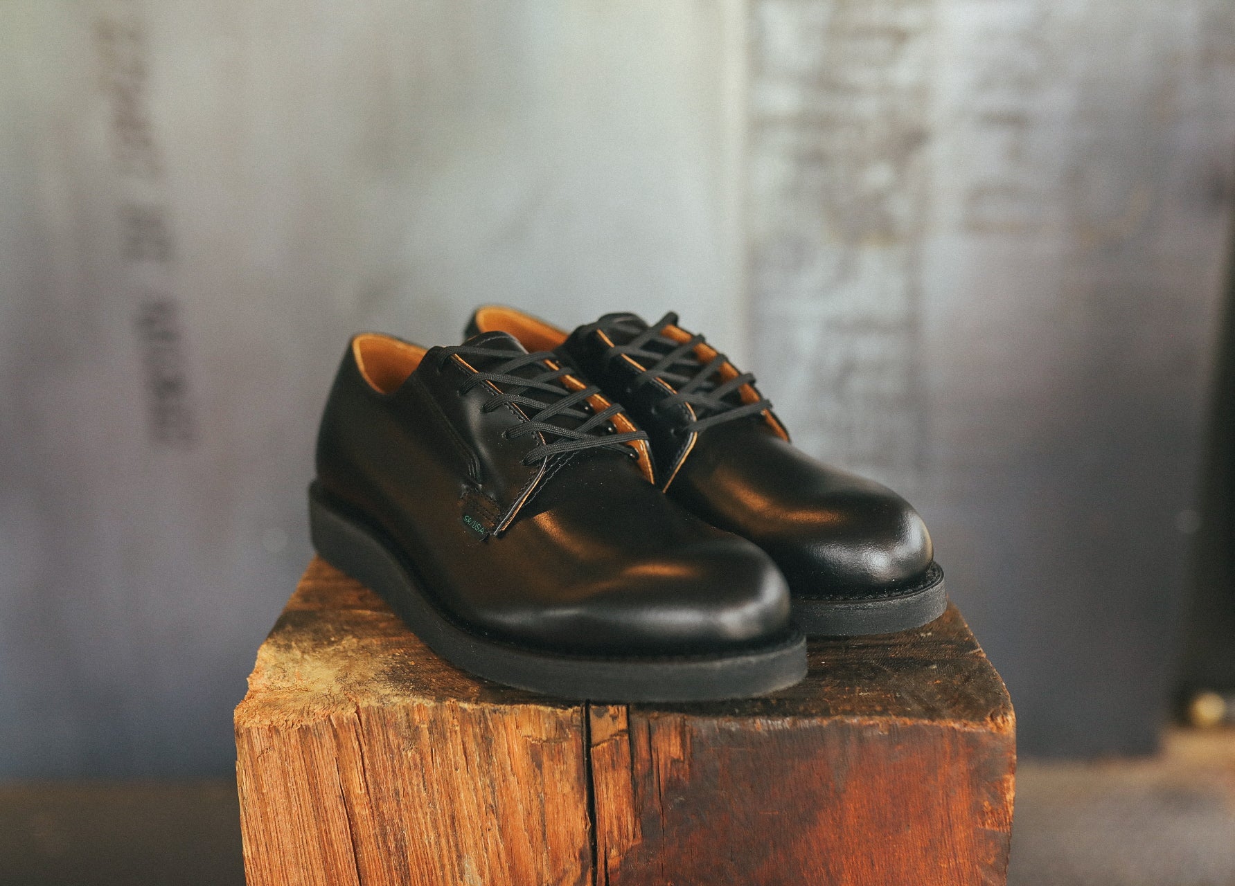 Pair of black leather Postman Oxfords with laces on rustic wooden block, Iron Shop Provisions