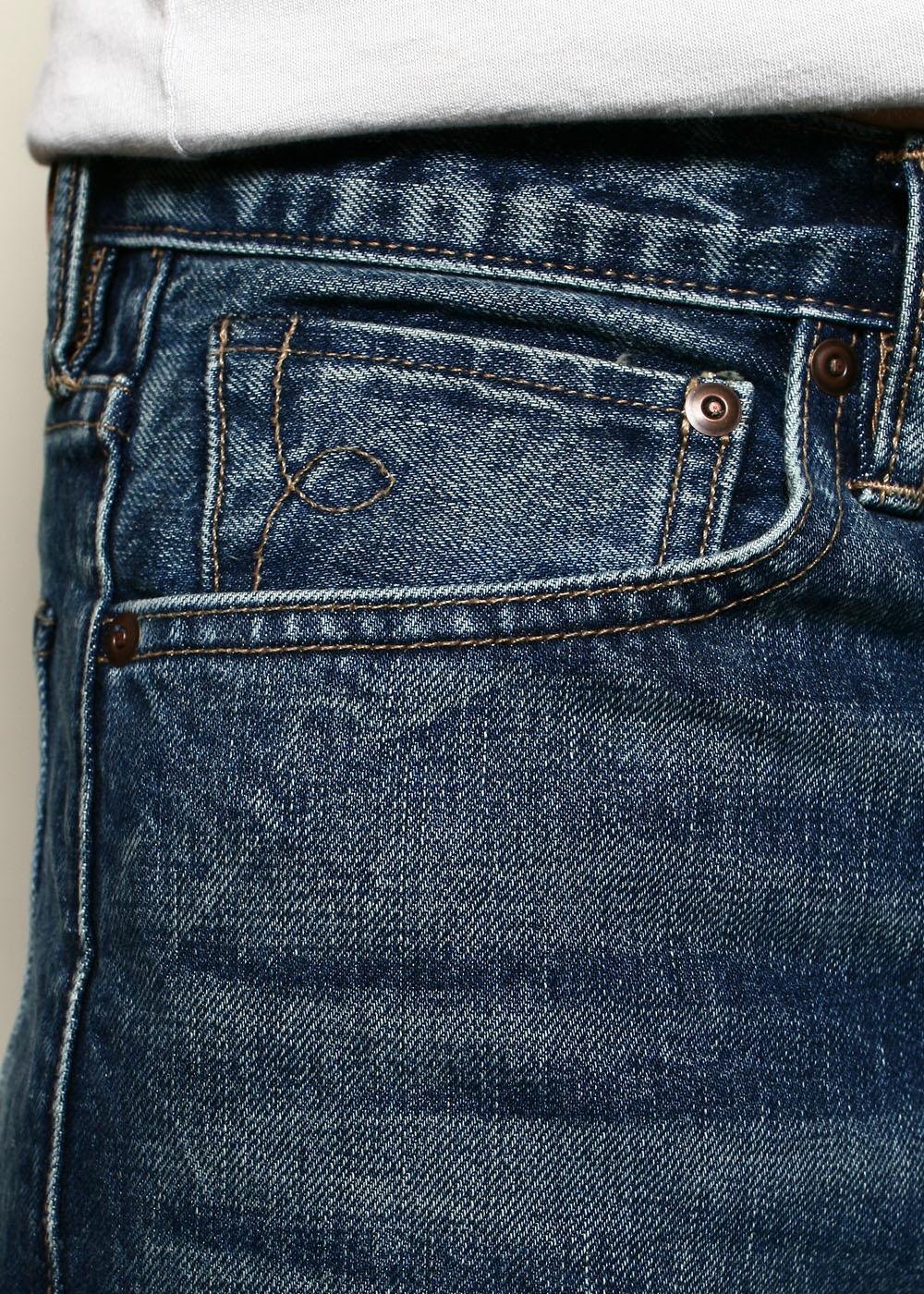 Close-up of blue denim jeans pocket with detailed stitching and copper rivets, casual wear style