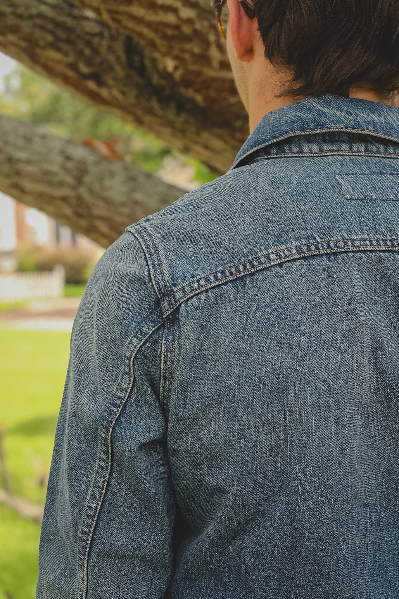 Person wearing a blue denim jacket with a blurred natural background