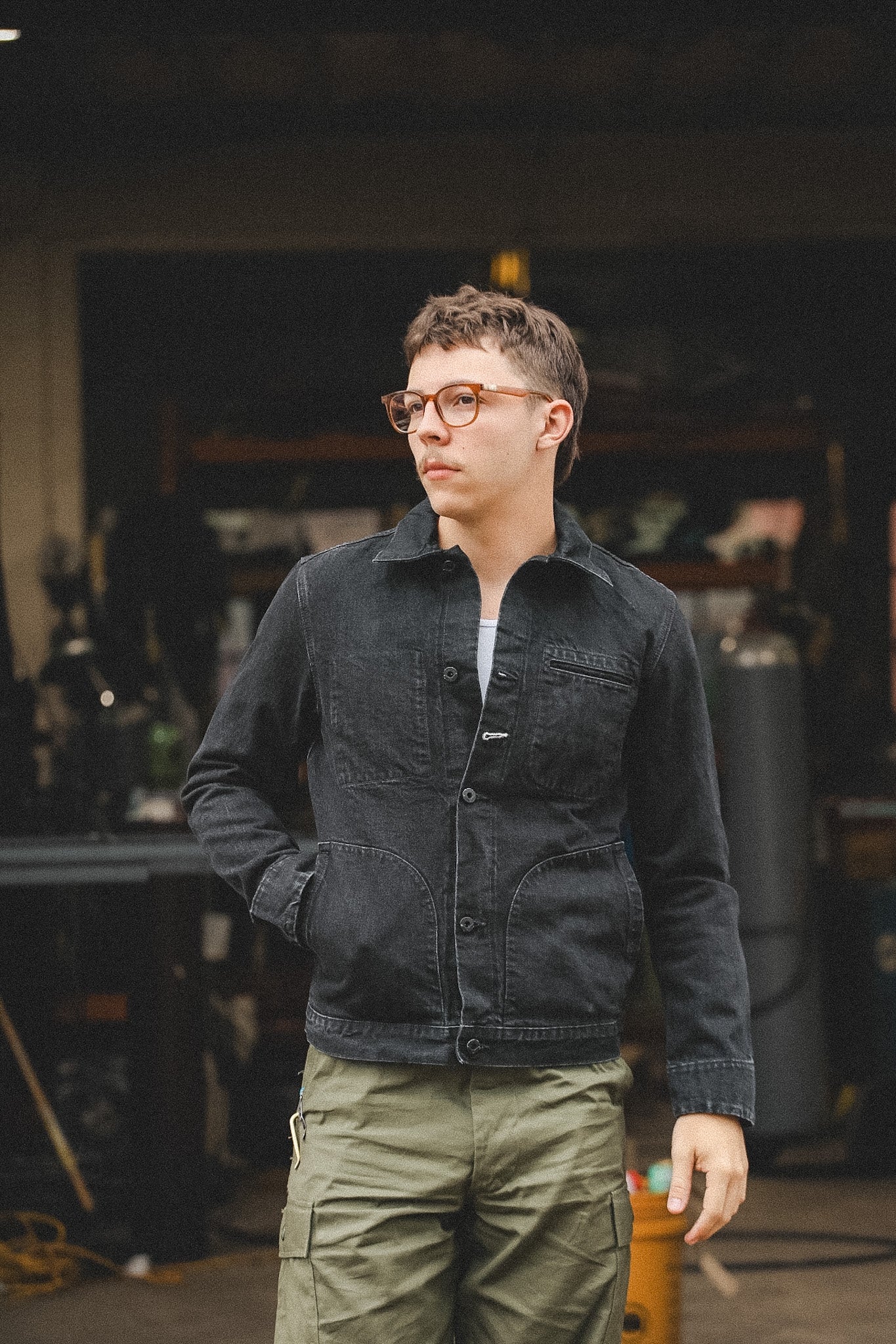Person wearing a dark jacket and green pants in an indoor setting