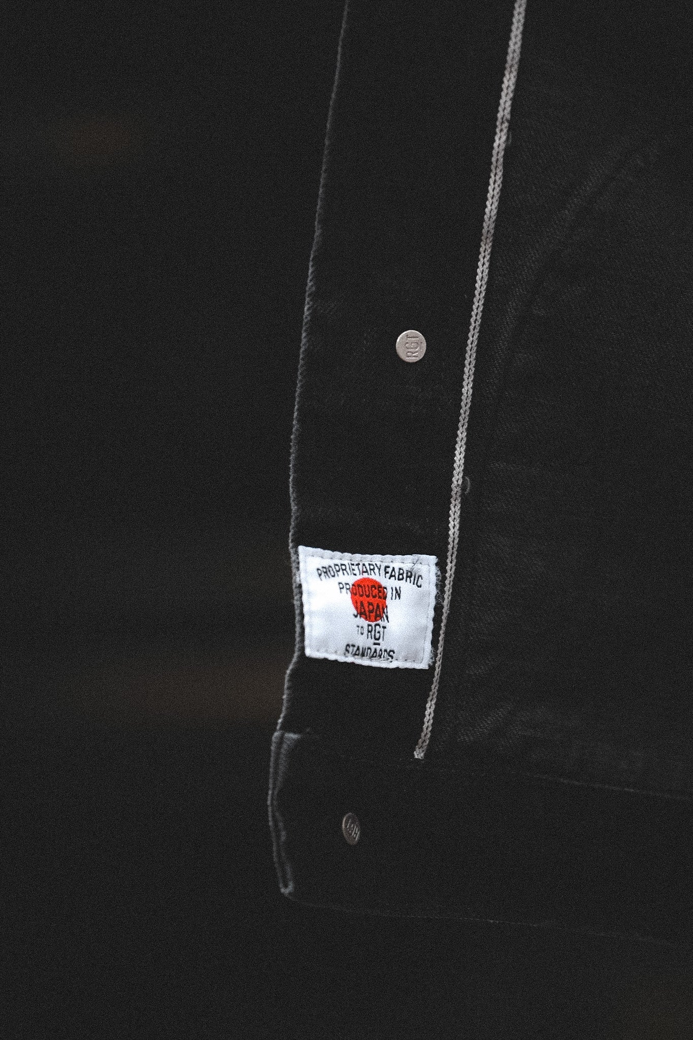 Close-up of a black jacket with a brand label on a dark background