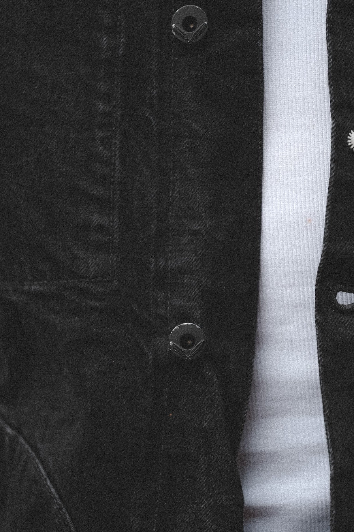 Close-up of a black corduroy jacket with white shirt underneath