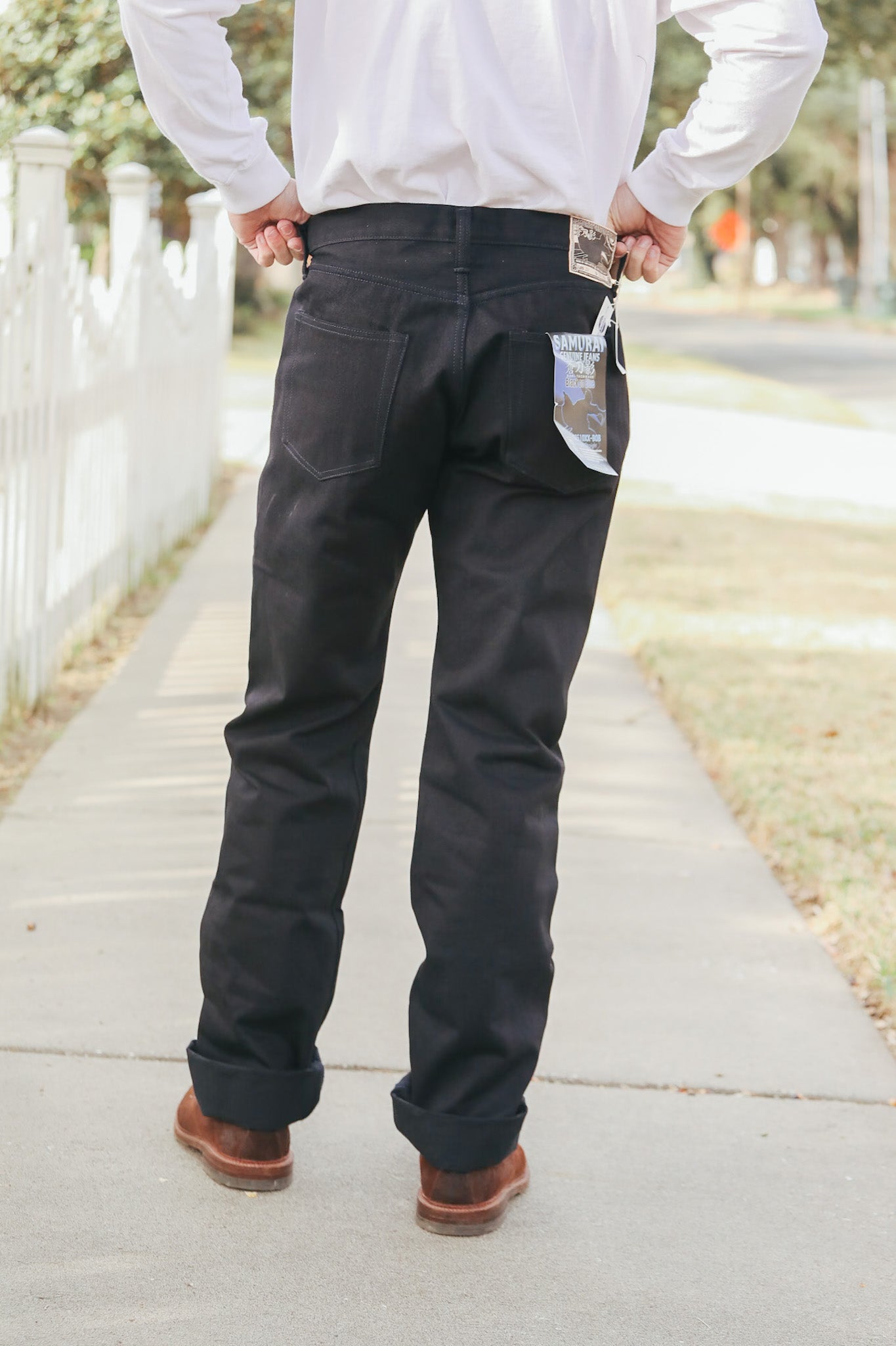 Person wearing black pants and a white shirt on a sidewalk.