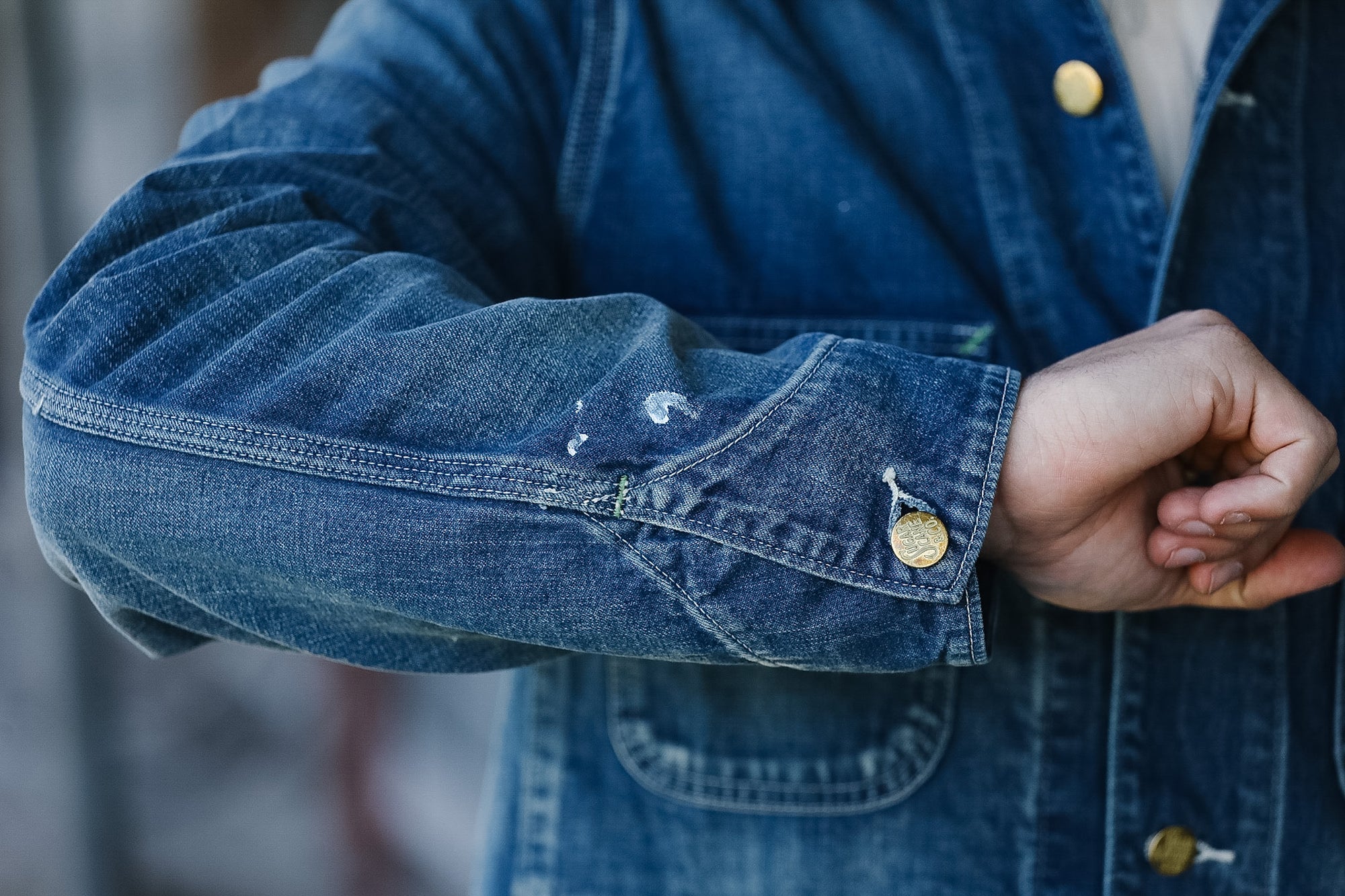 Close-up of a person wearing a blue denim jacket with rolled-up sleeves.