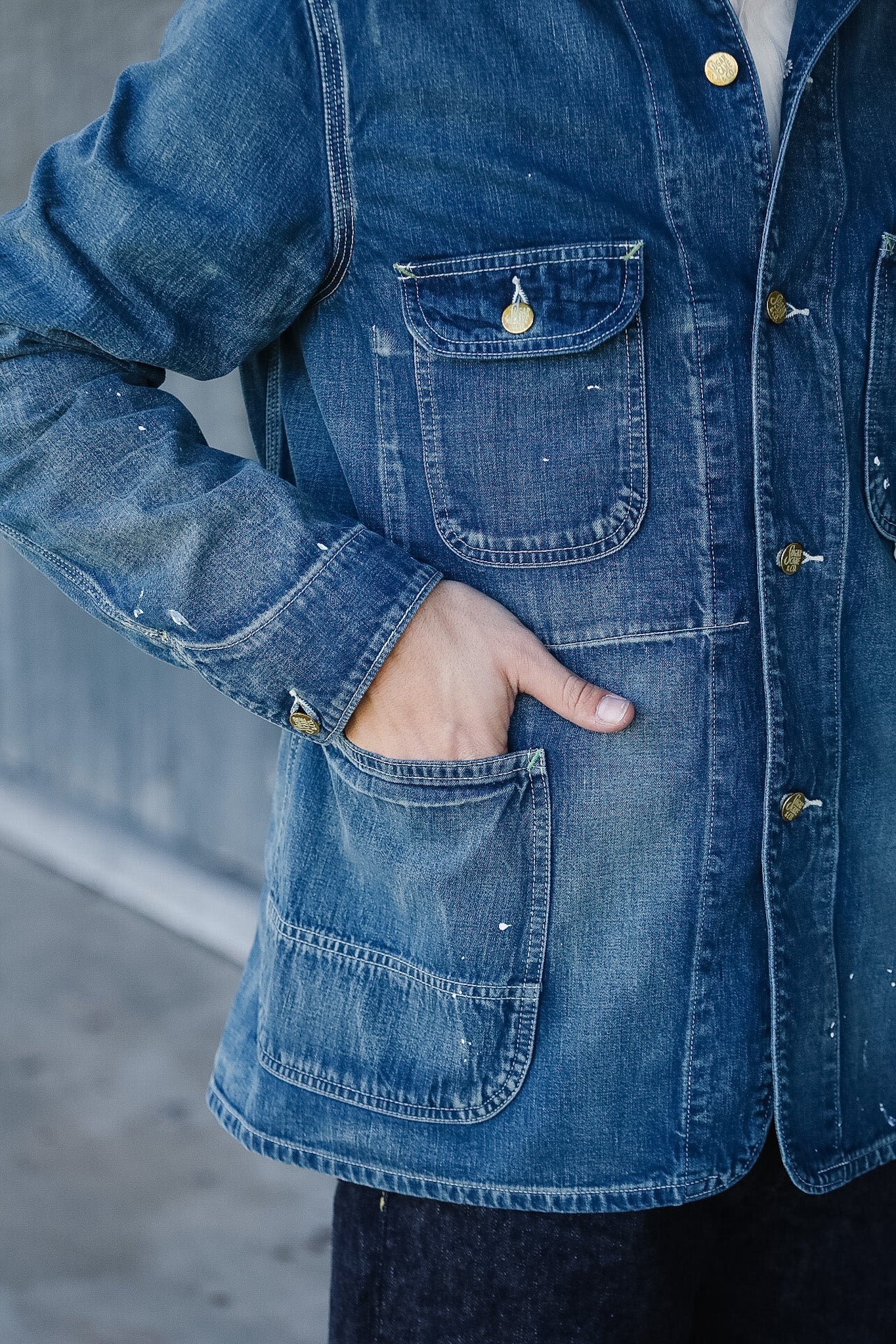 Close-up of a person wearing a blue denim jacket with visible buttons and pockets.