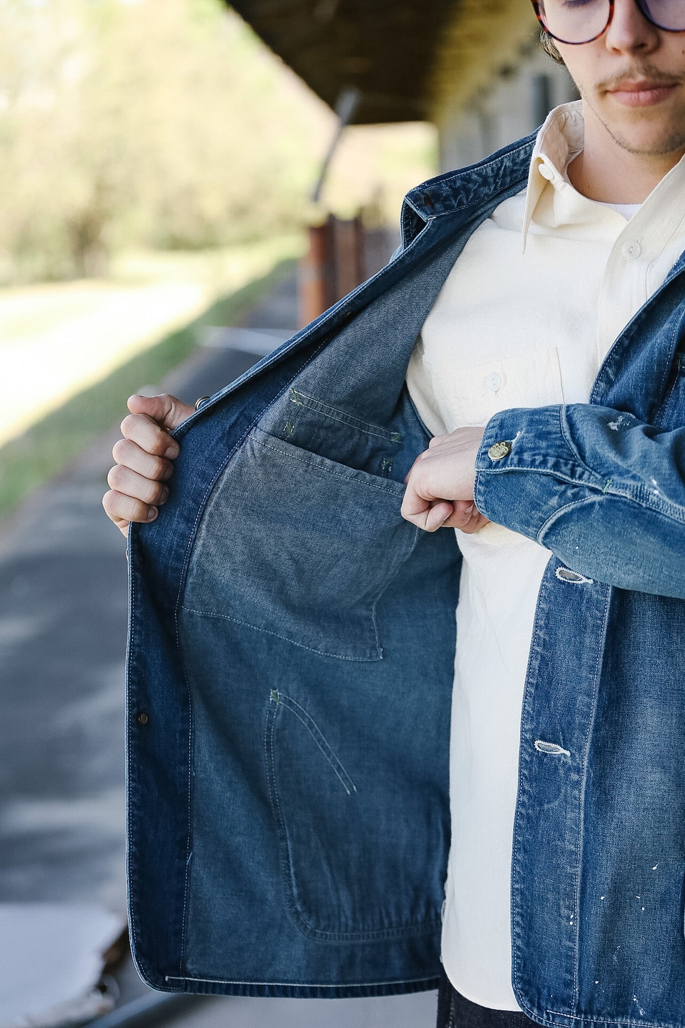 Person wearing a blue denim jacket with a blurred outdoor background