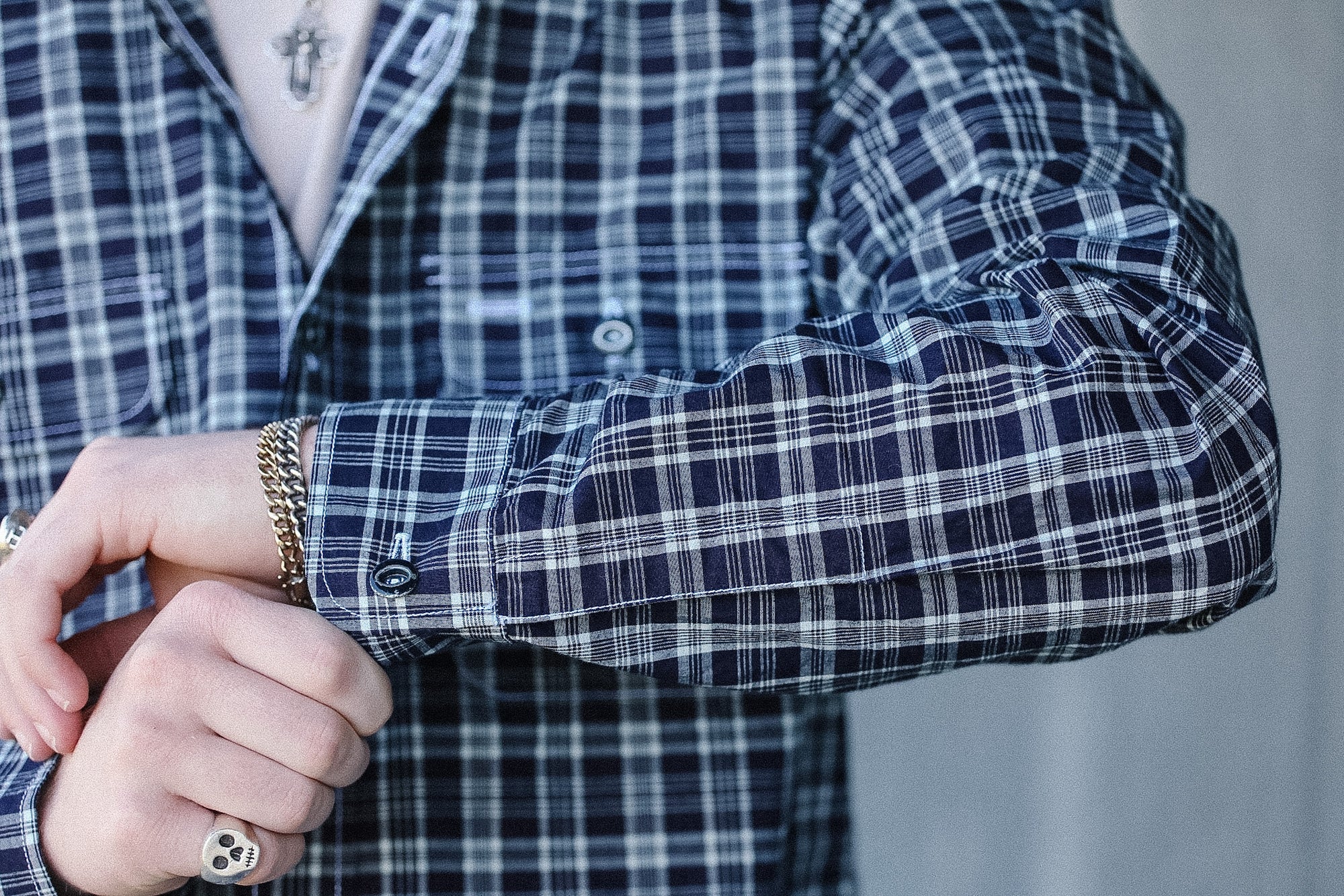 Person wearing a blue and white plaid shirt with rolled-up sleeves, focusing on the arm and hand.