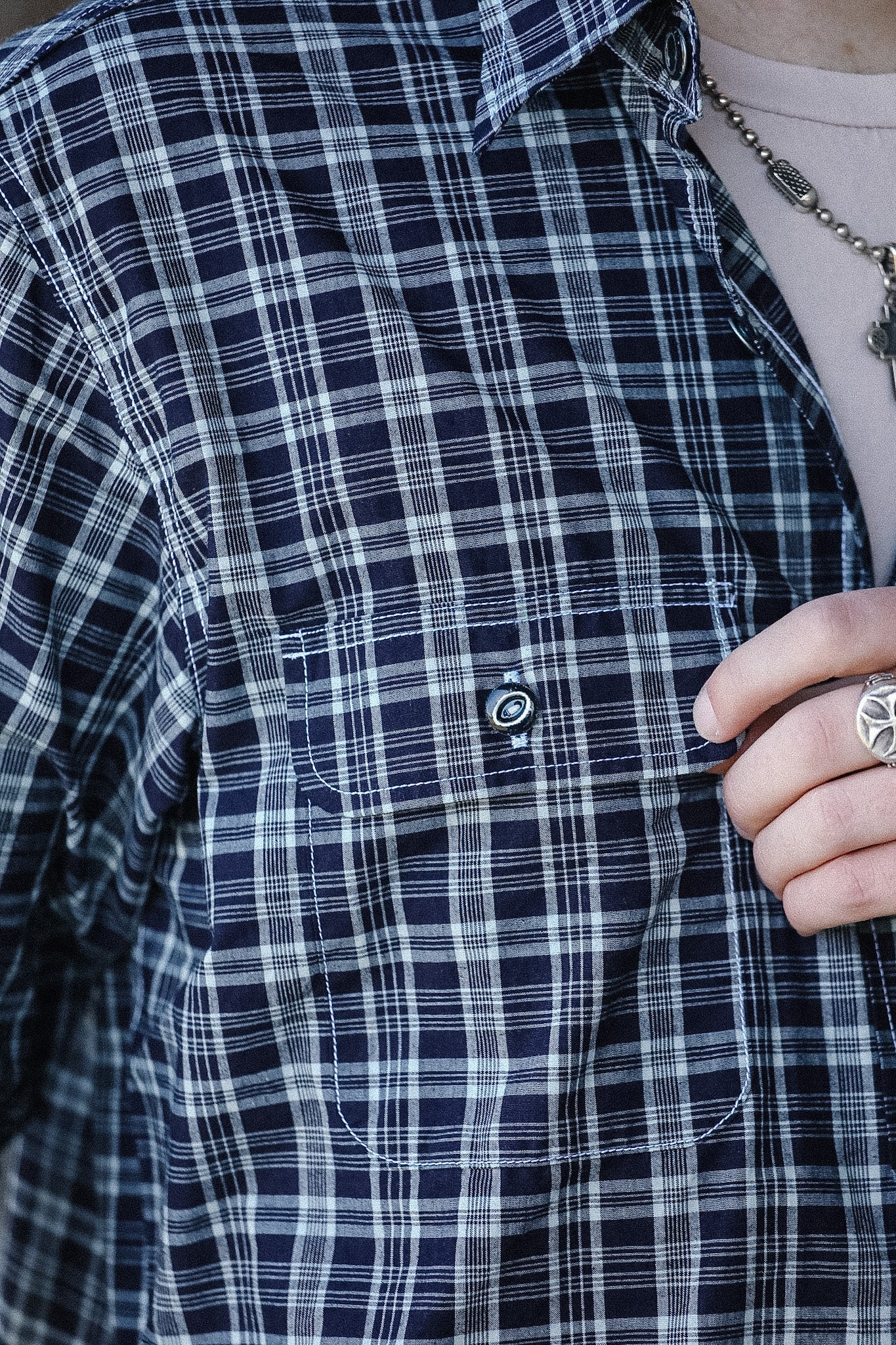 Close-up of a person wearing a blue and white plaid shirt with a focus on the collar and buttons.