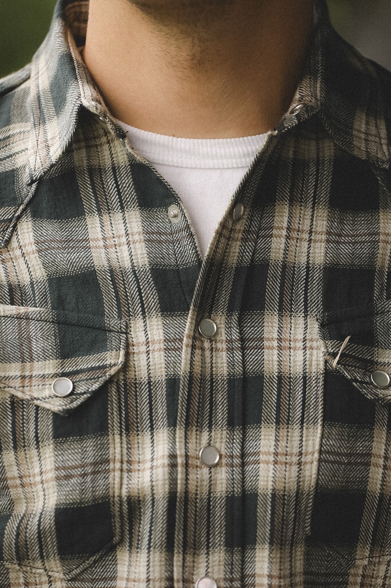 Close-up of a person wearing a plaid shirt with a neutral background