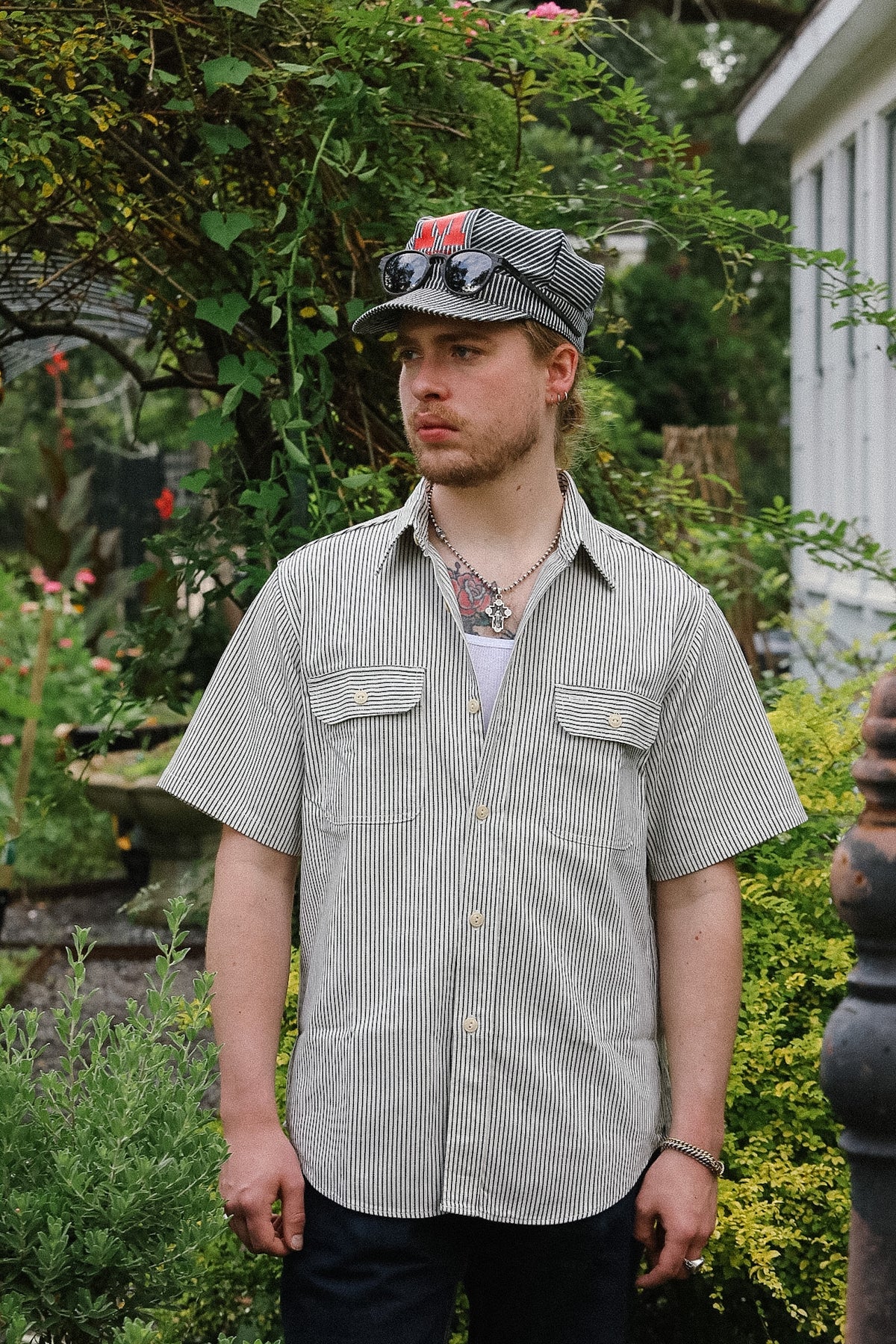 Man wearing a striped shirt and cap standing in a garden