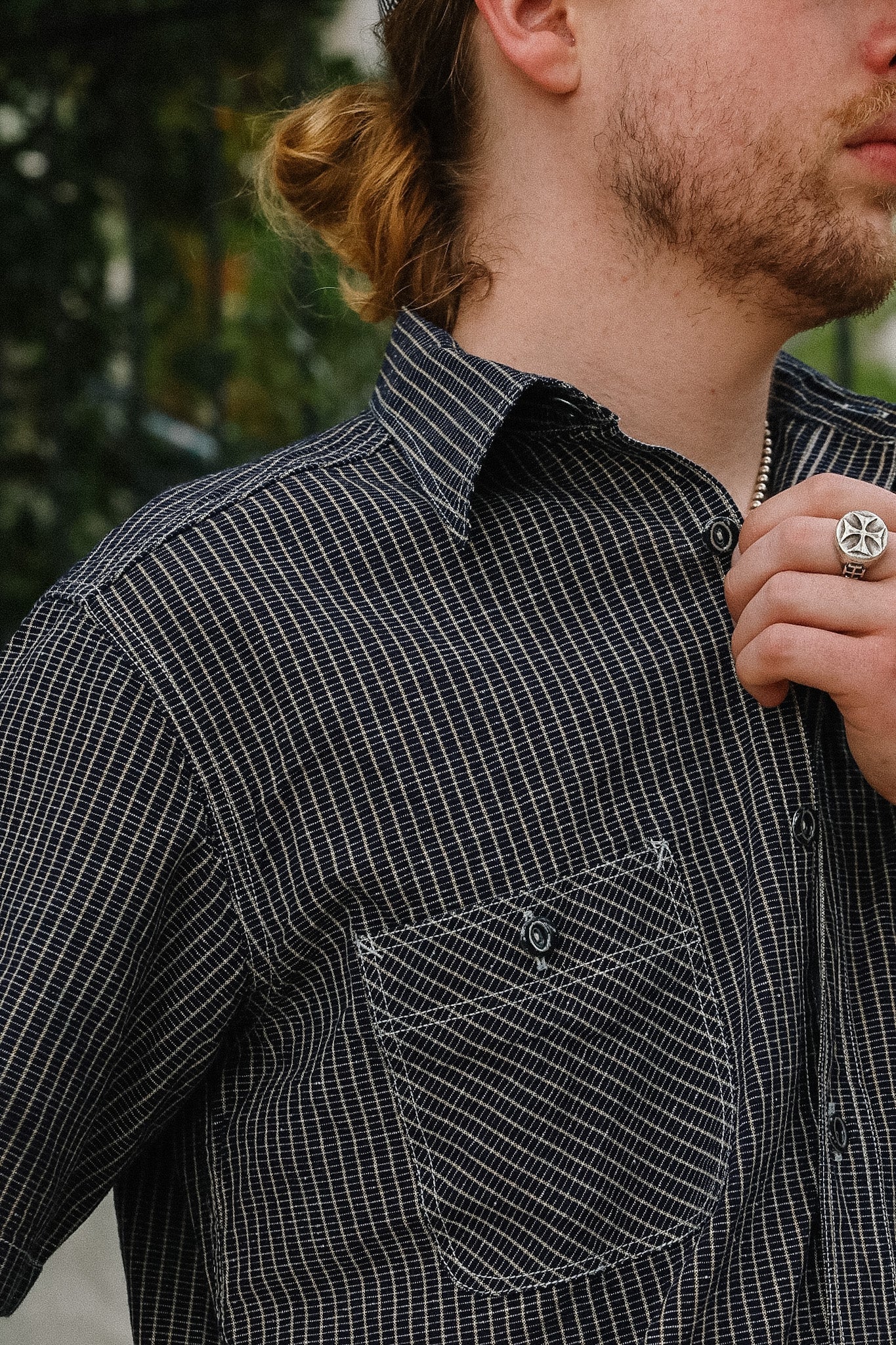 Person wearing a black and white checkered shirt with a blurred background