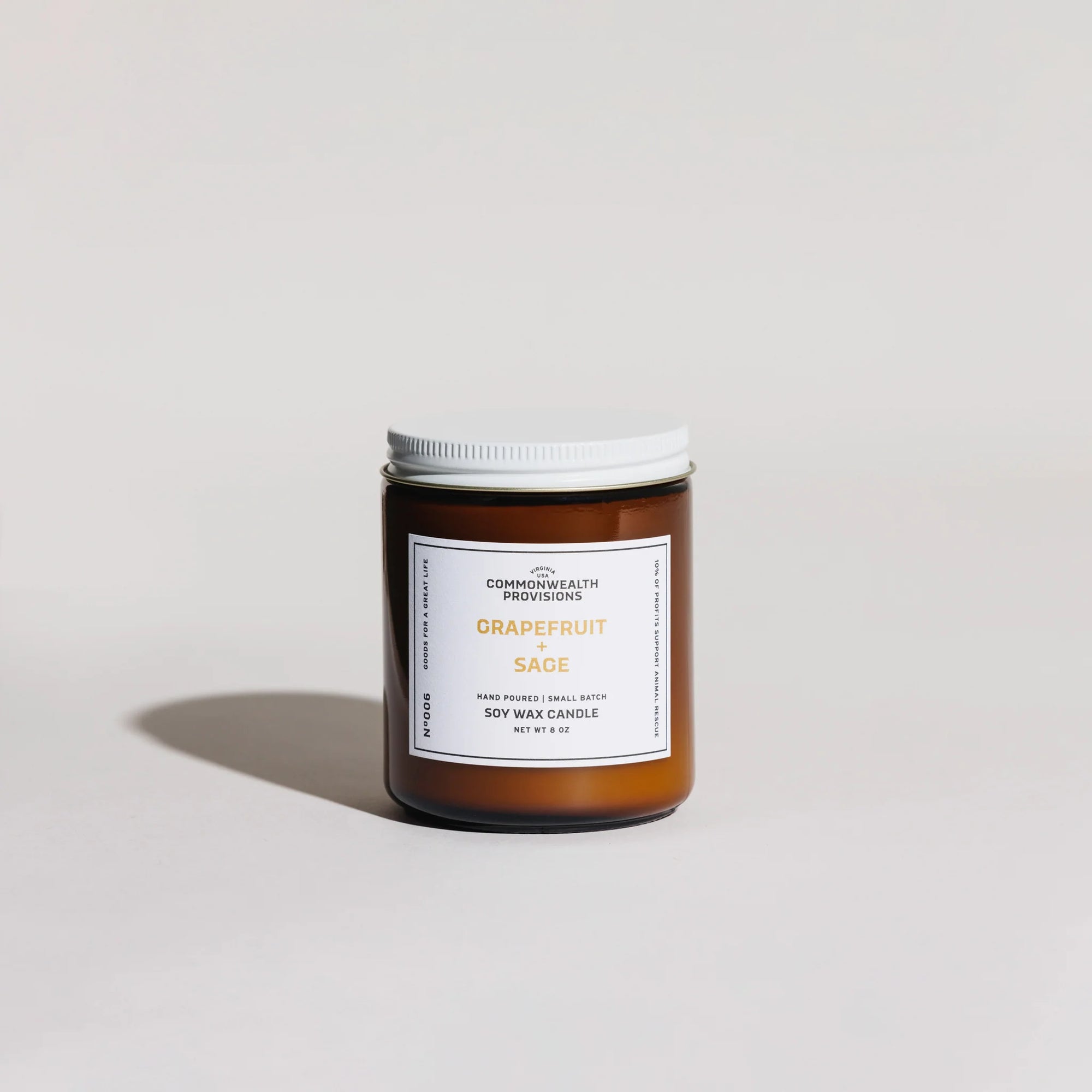 Amber glass jar soy wax candle with white lid labeled Grapefruit and Sage by Commonwealth Provisions on white background