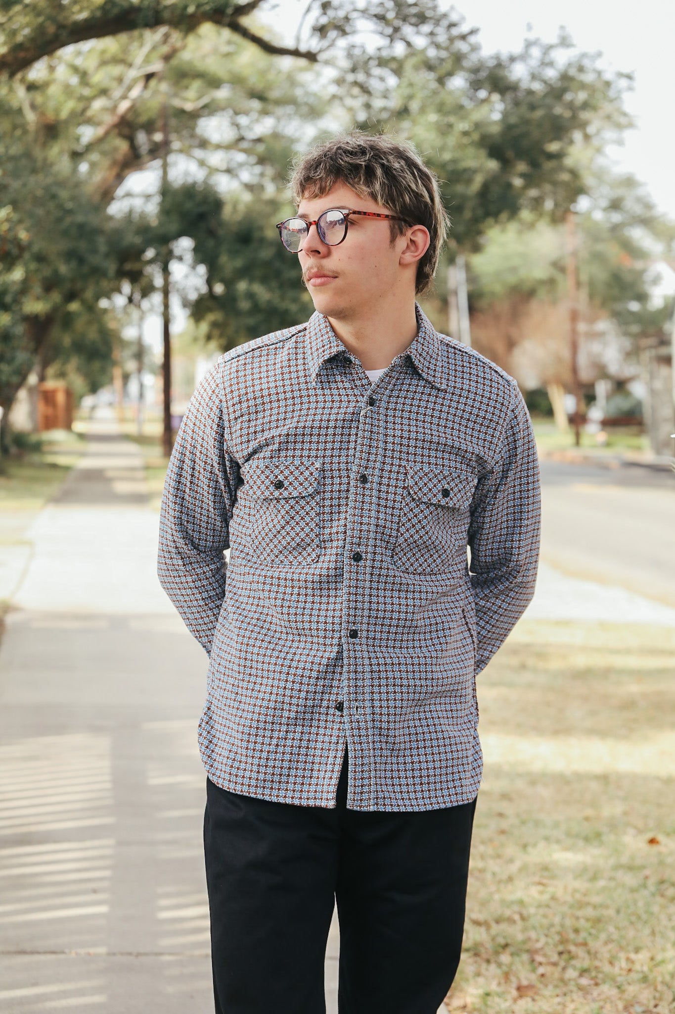 Person wearing a checkered shirt outdoors on a sunny day