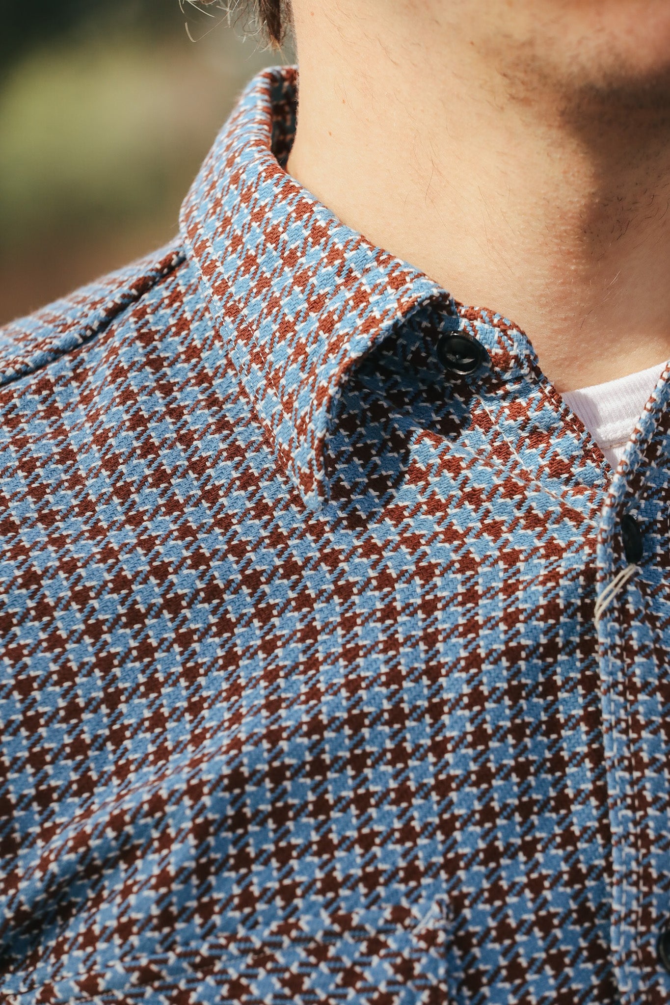 Close-up of a person wearing a patterned shirt with a blurred background