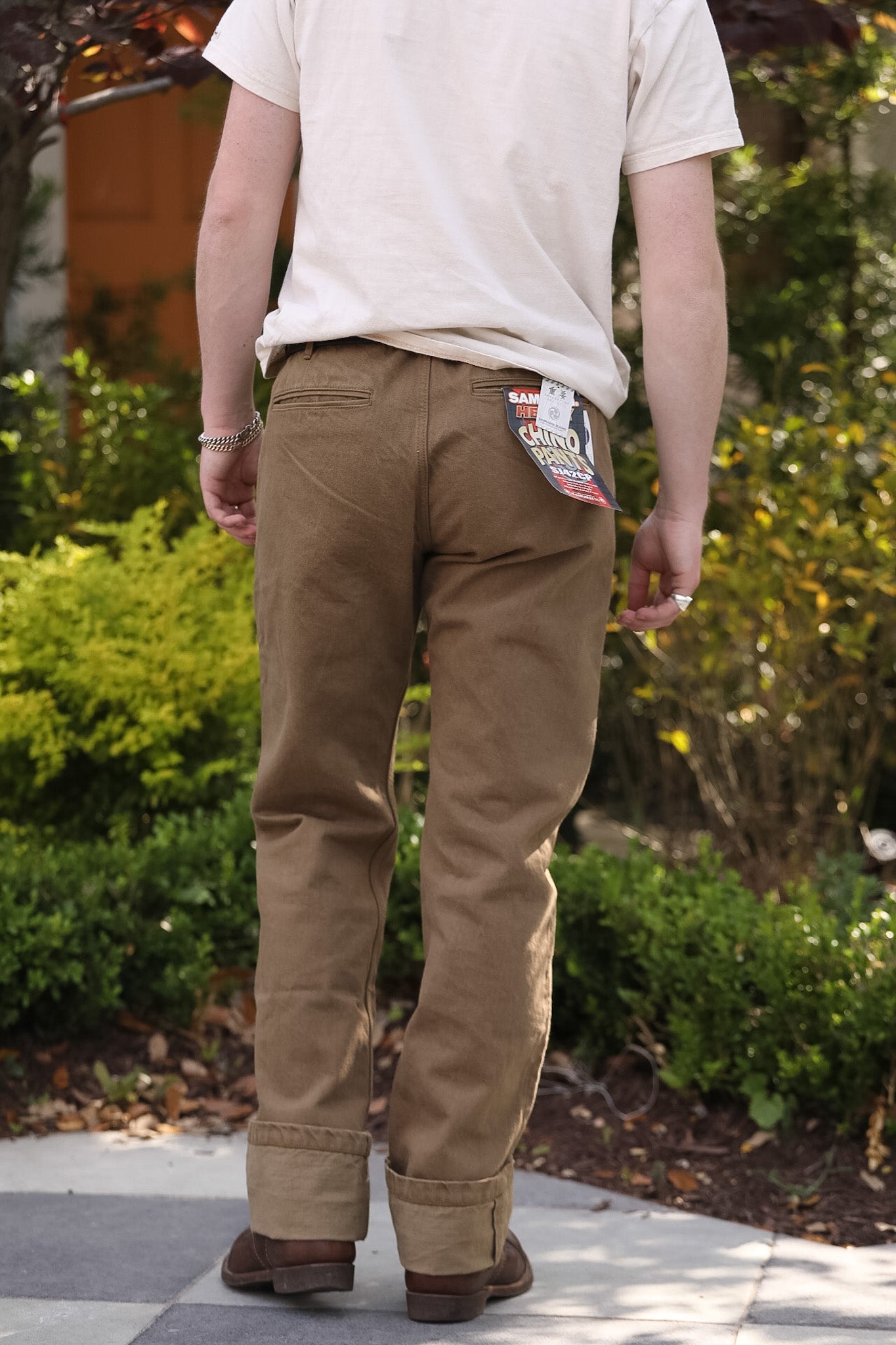 Person wearing brown pants with a patch on the back pocket, standing outdoors.