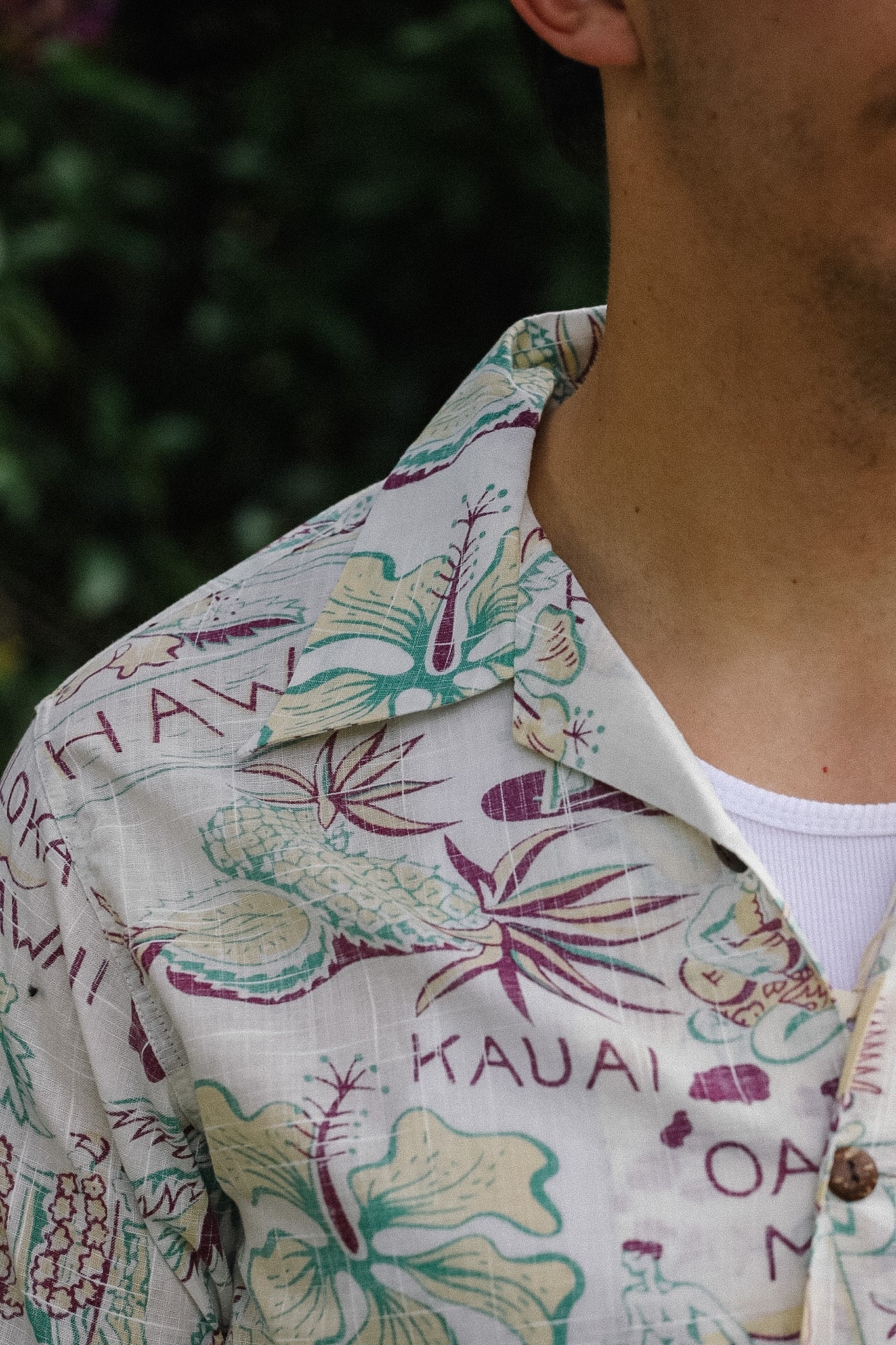 Close-up of a person wearing a floral shirt with 'Kauai' text.