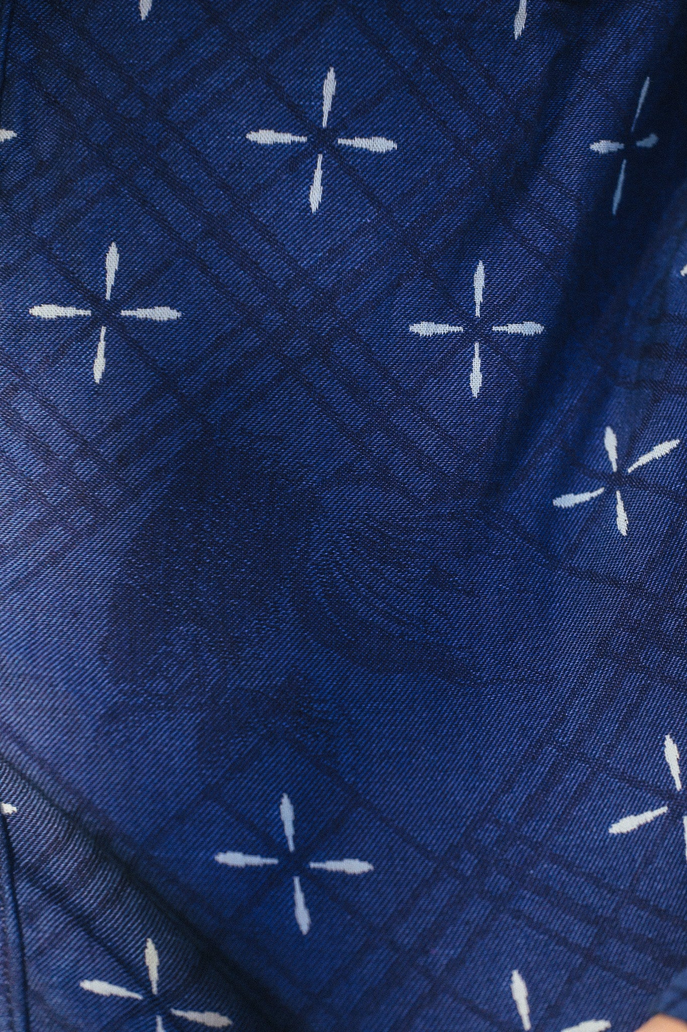 Close-up of indigo jacquard work shirt fabric with subtle goldfish pattern and white cross motifs
