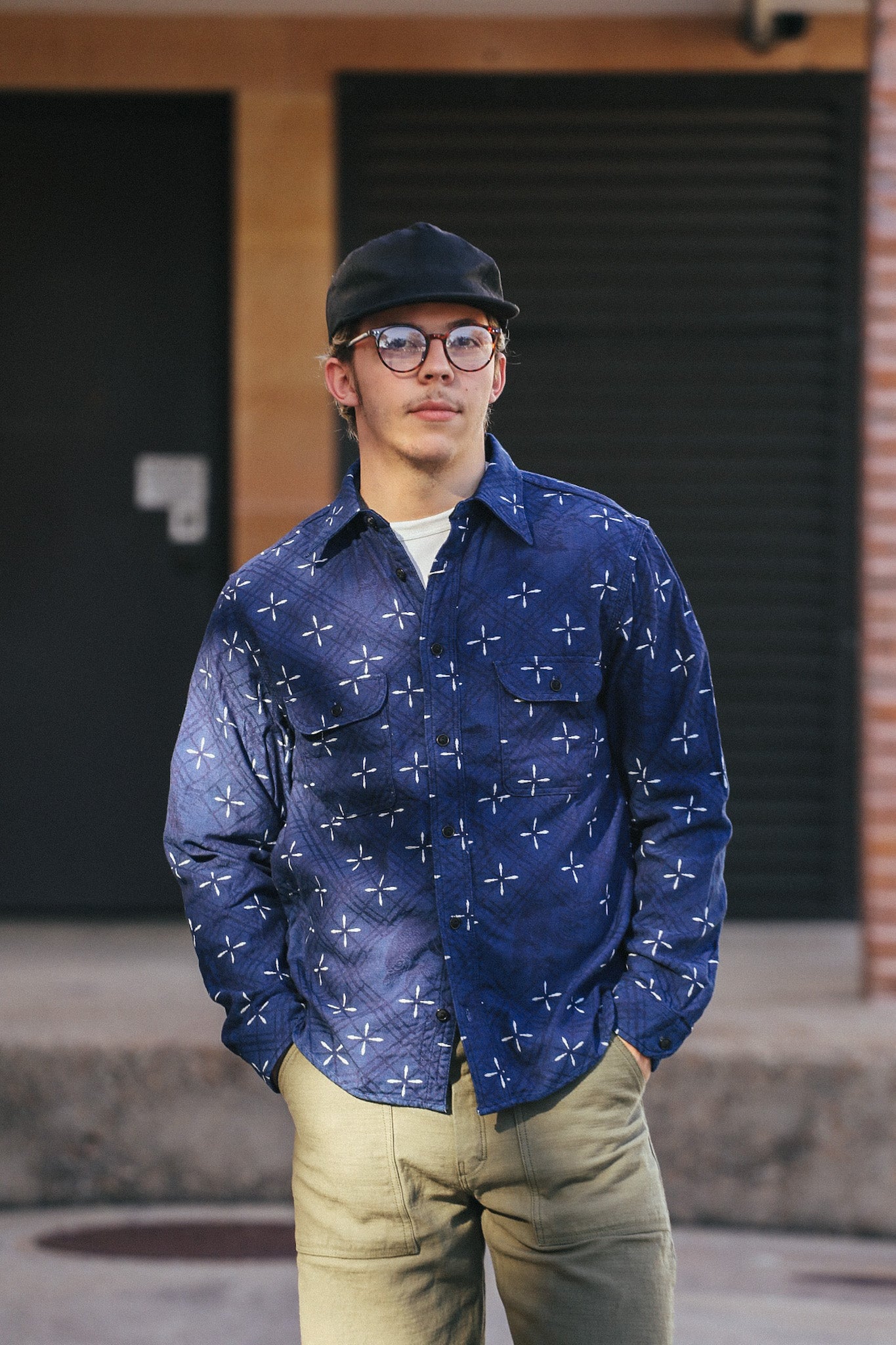 Man wearing blue Narihirabishi goldfish pattern jacquard work shirt with front pockets, khaki pants, black cap, and glasses